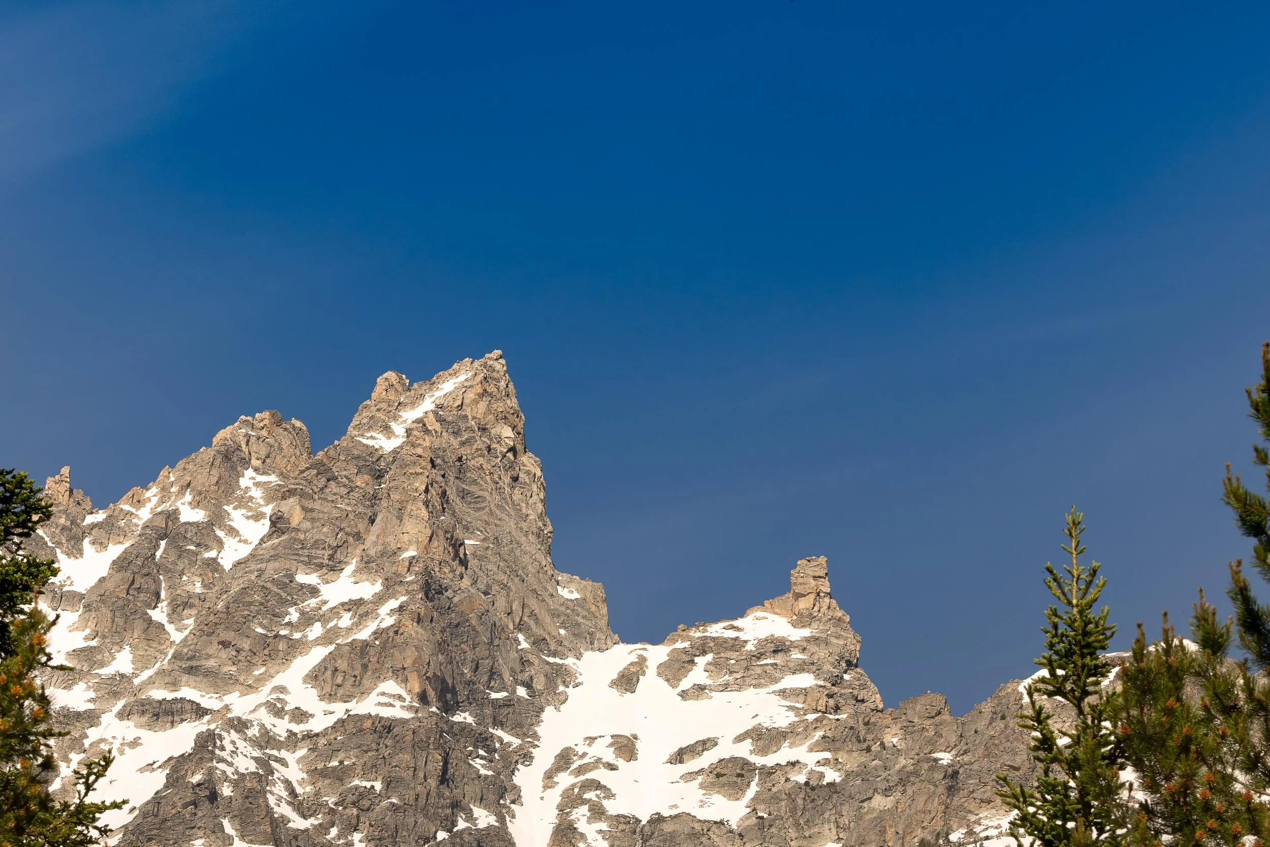  Where Granite Meets the Sky 
Skirting the edge of Jenny Lake, the world falls perfectly silent as the jagged peaks of the Grand Tetons break through the morning haze. This fleeting moment captures the immense, humbling scale of the alpine wilderness