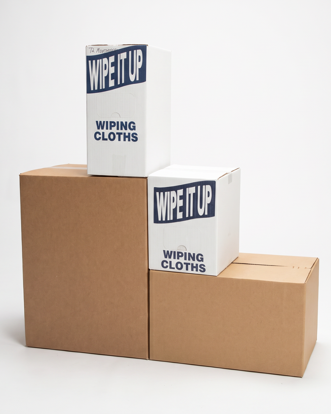 Two cardboard boxes and two boxes of wipe it up wiping cloths stacked on top of each other on a plain white background.