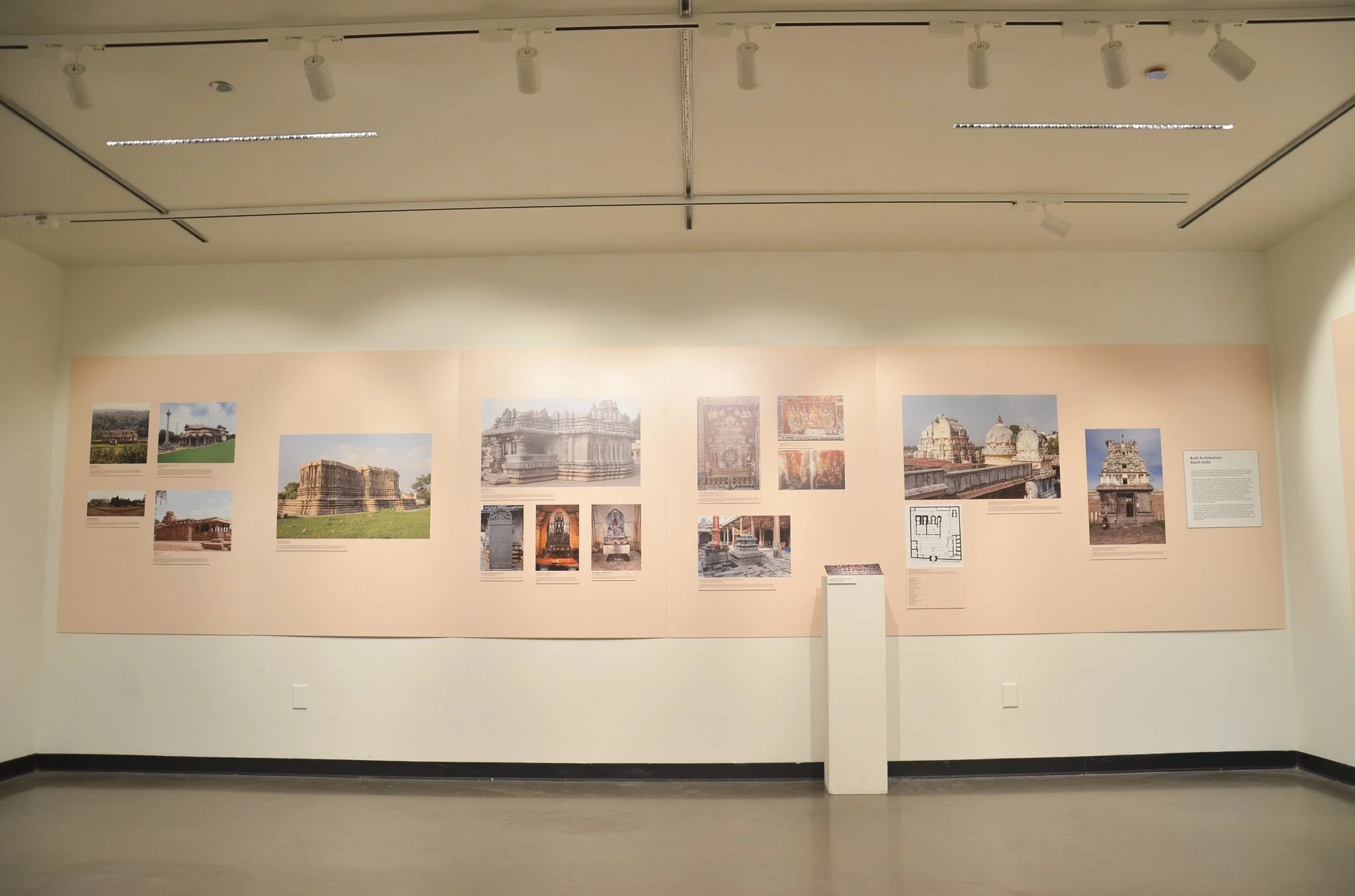 Museum exhibit with photographs and informational plaques about South Indian architecture, featuring images of temples and architectural plans.
