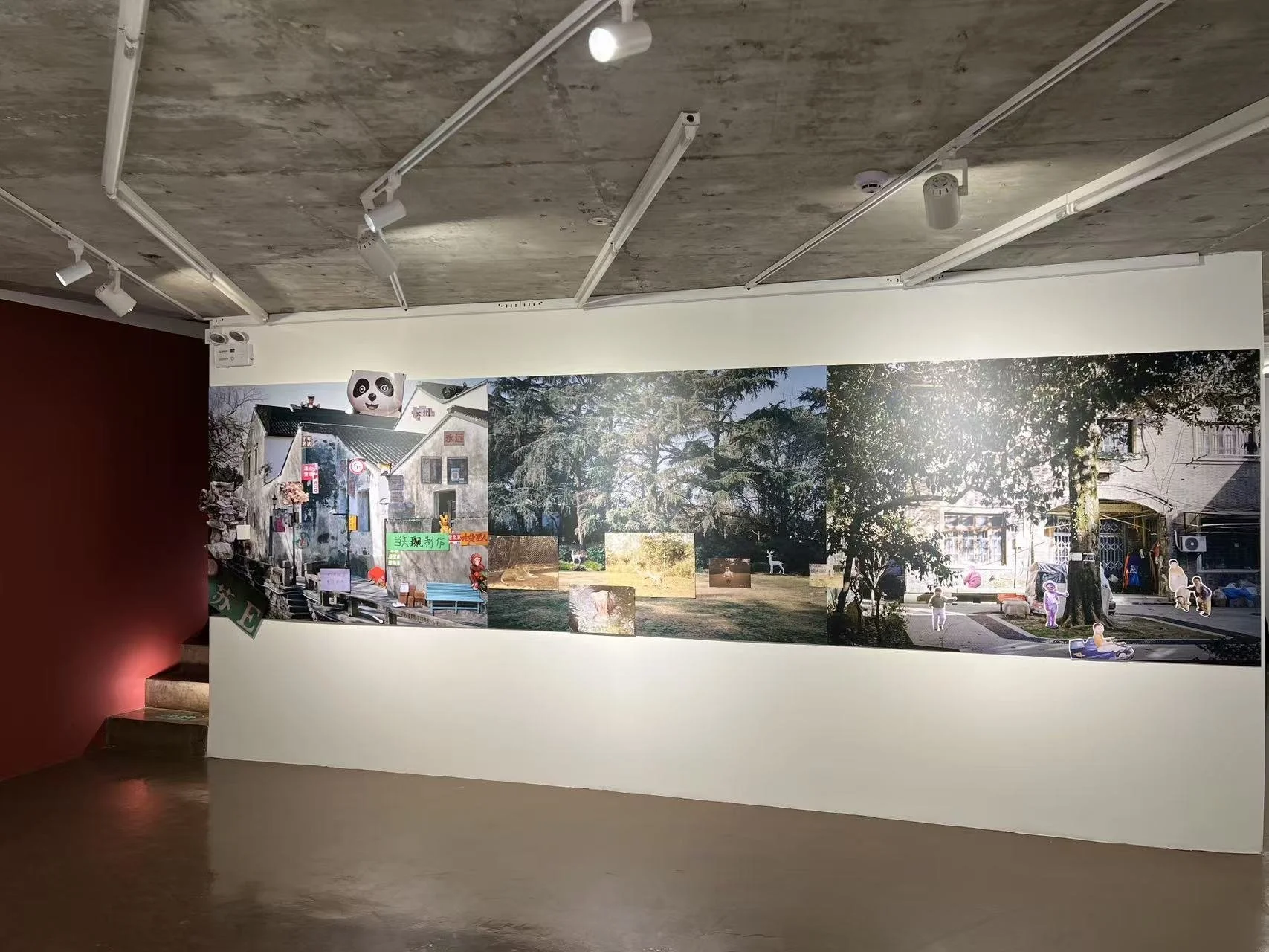 Museum or gallery wall displaying a large collage of outdoor scenes, including trees, buildings, and people, with some decorative elements and signs.