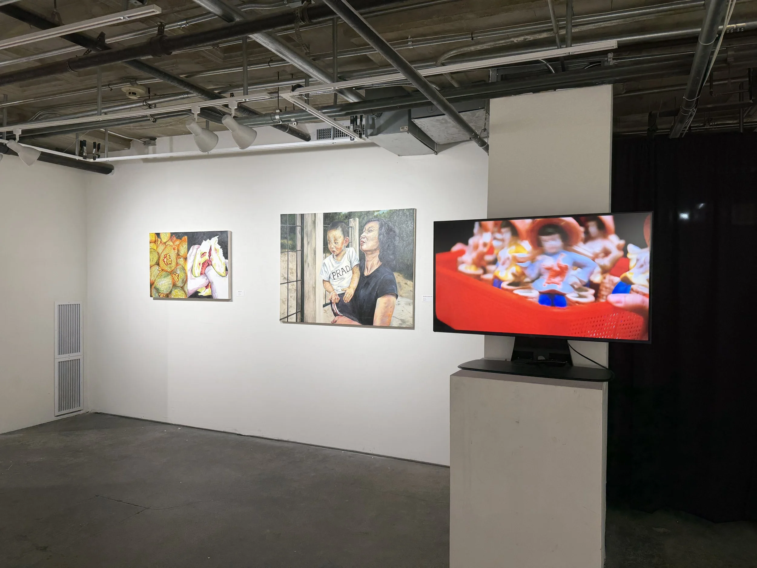 Gallery wall with four paintings, a large flat screen TV showing colorful scene, and exposed ceiling pipes and ducts.