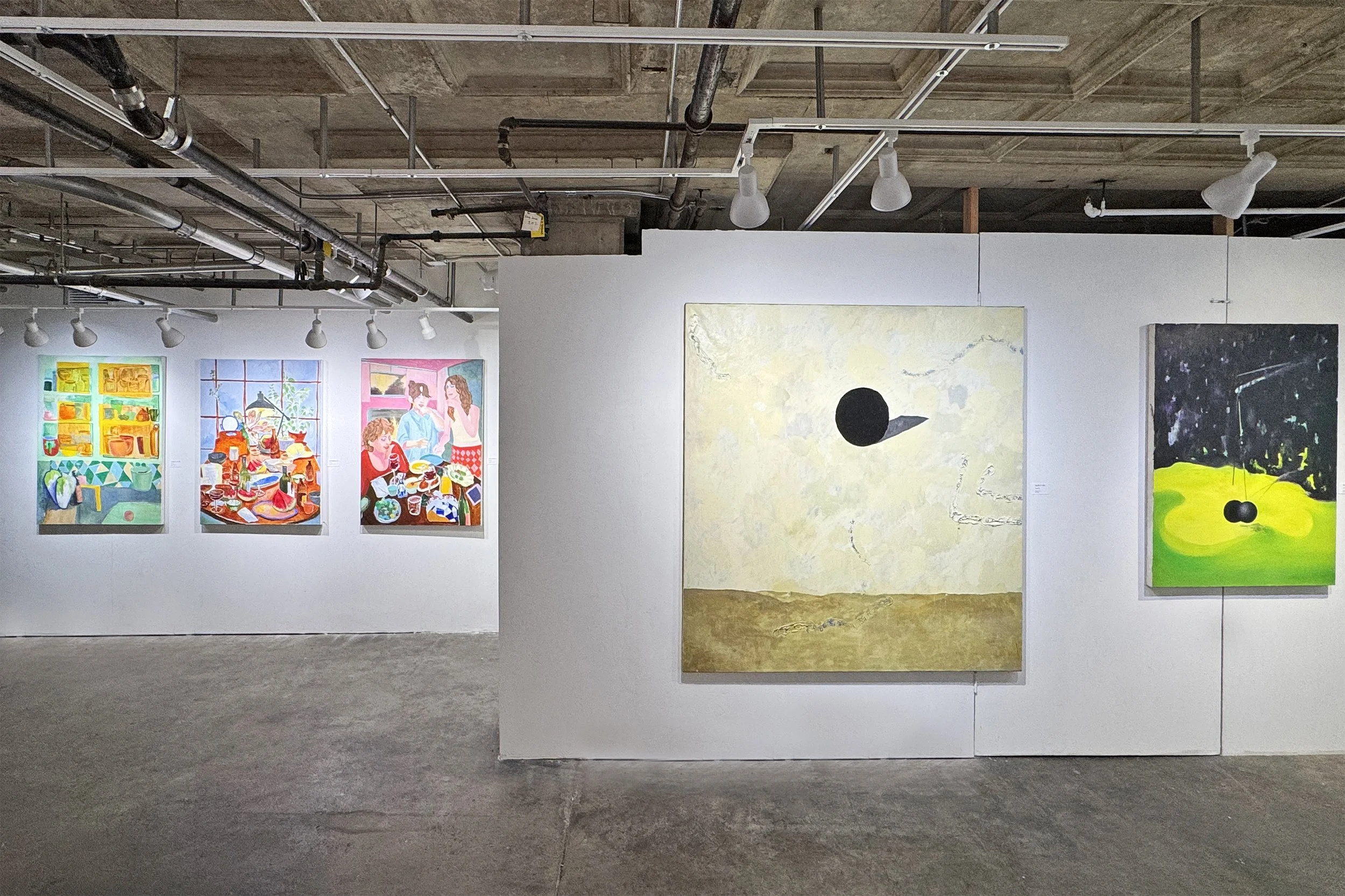Art gallery featuring colorful paintings on a white wall, including abstract depictions of people and objects, with track lighting illuminating the artwork.