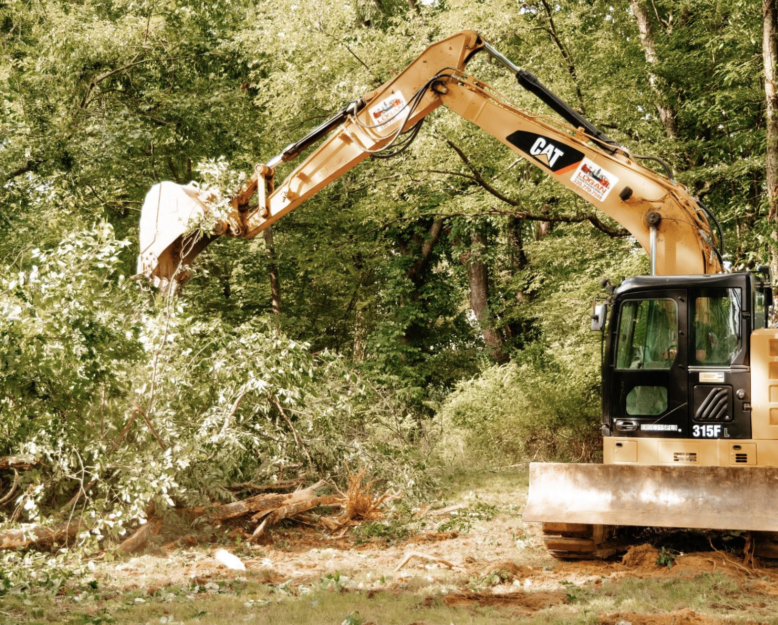 Heavy equipment clearing brush, trees, and vegetation during a land improvement project in Beaver Falls, Pennsylvania.