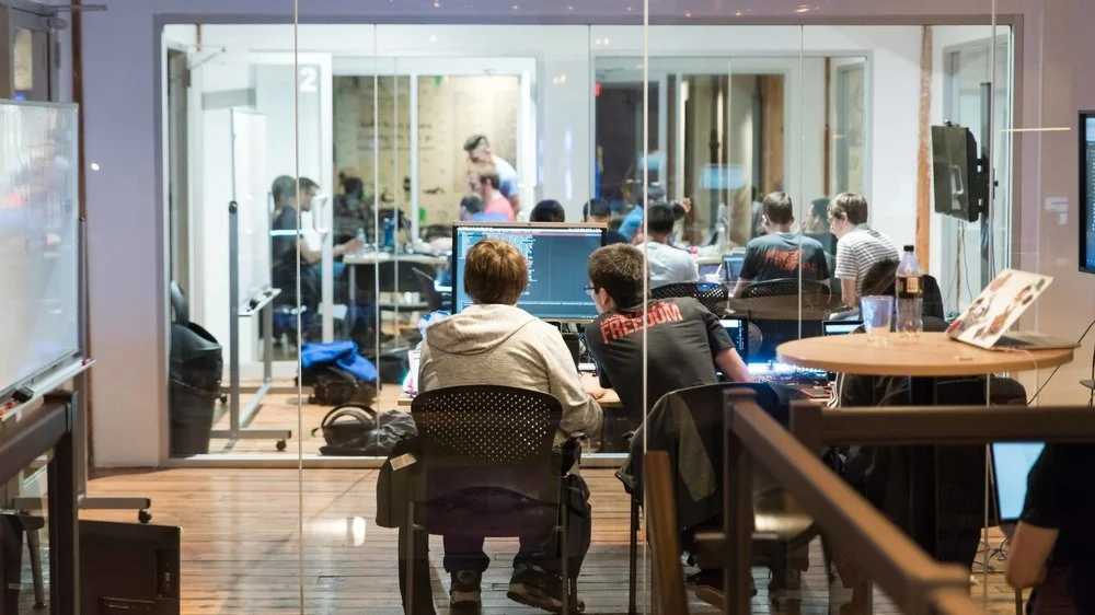 People working and attending a meeting in an office conference room with a glass wall.