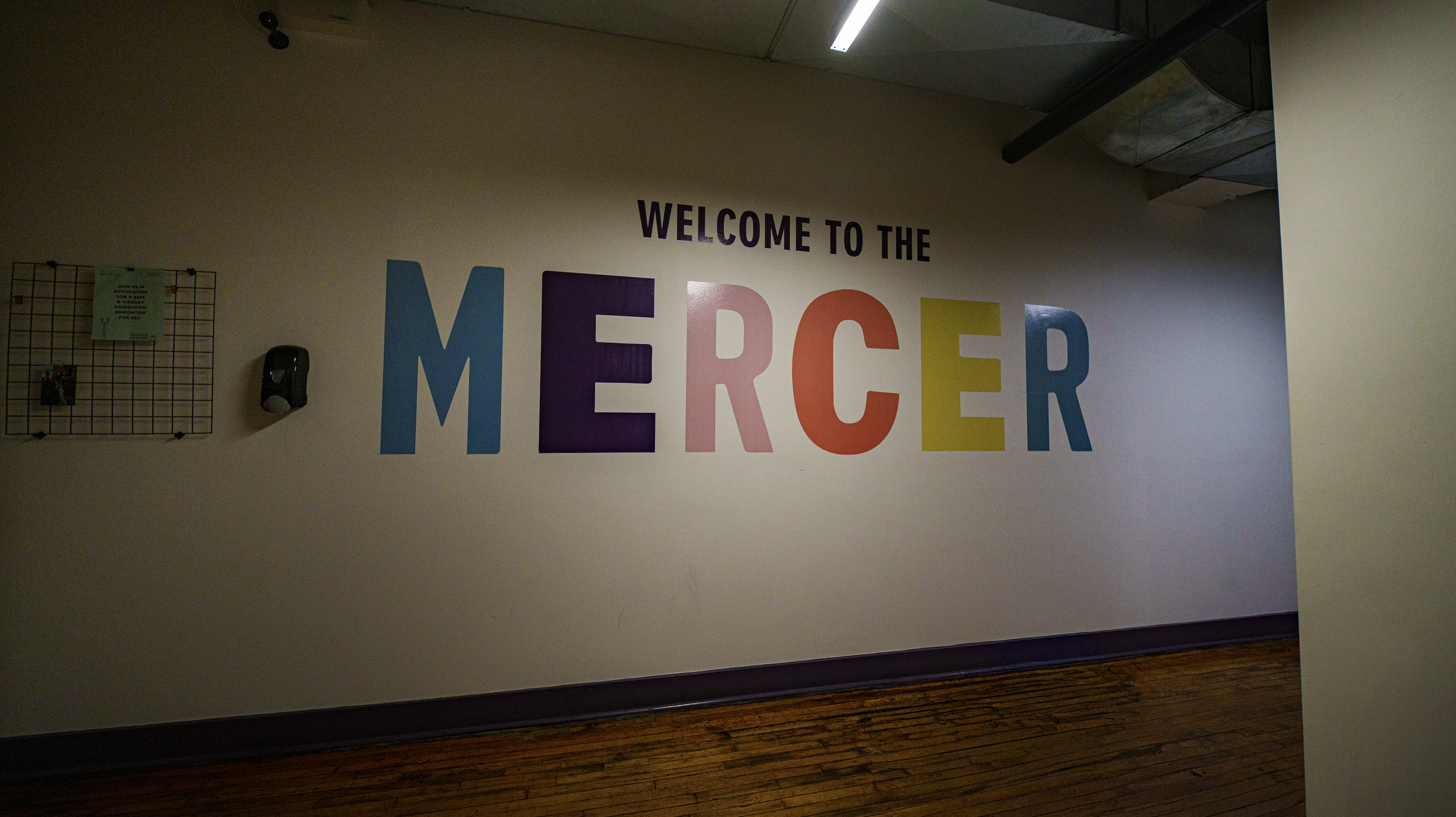 Colorful sign on a wall that reads, "WELCOME TO THE MERCER" in purple, pink, orange, yellow, and blue letters.