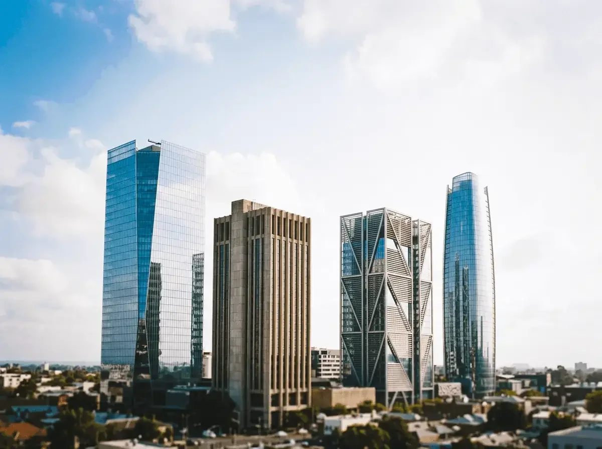 City skyline with modern tall buildings and skyscrapers under a partly cloudy sky.