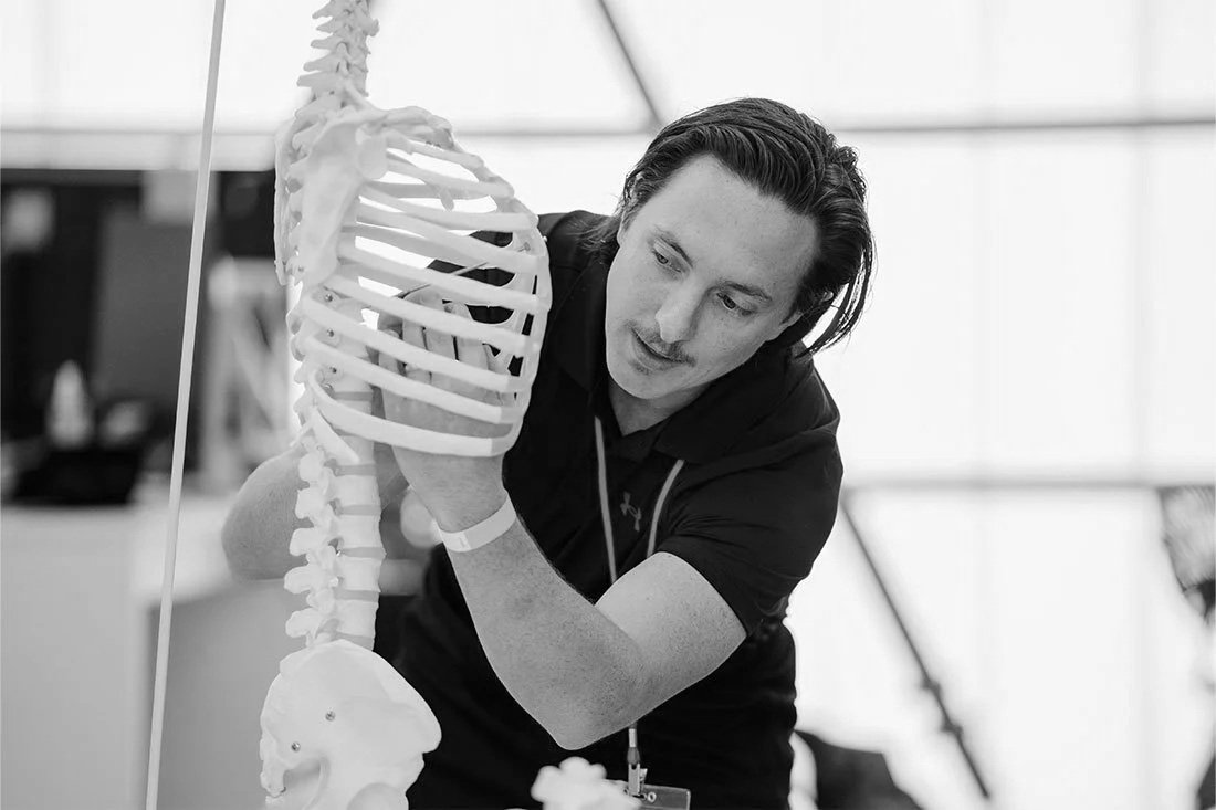 Man examining a human spine model in a laboratory or educational setting.