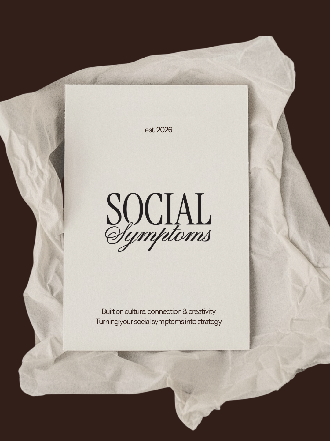 A book titled 'Social Symptoms' on a crumpled paper backdrop, with the subtitle 'Built on culture, connection & creativity. Turning your social symptoms into strategy'.