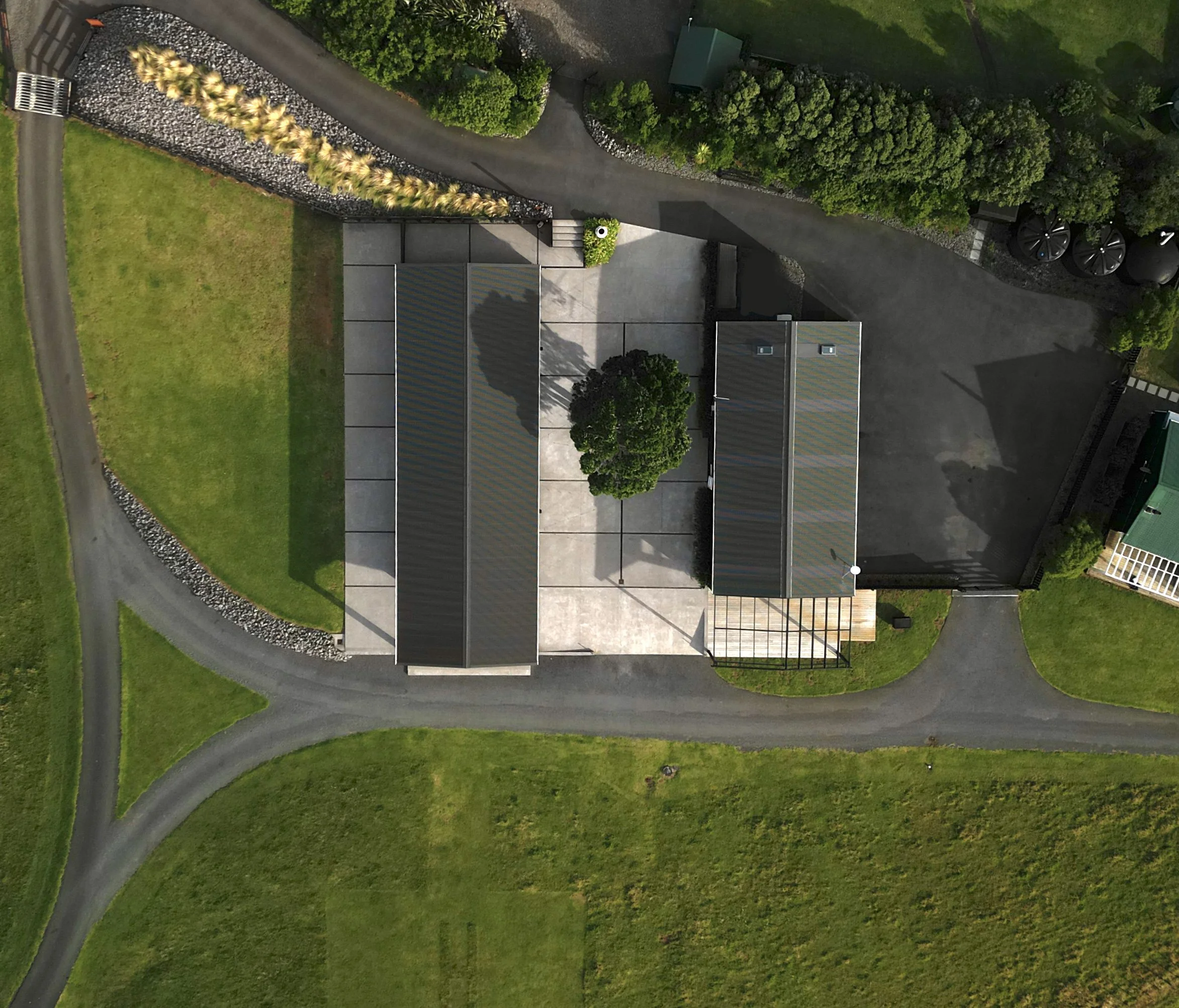 Aerial view of a modern home, landscaped yard, curved driveway, and surrounding green lawn