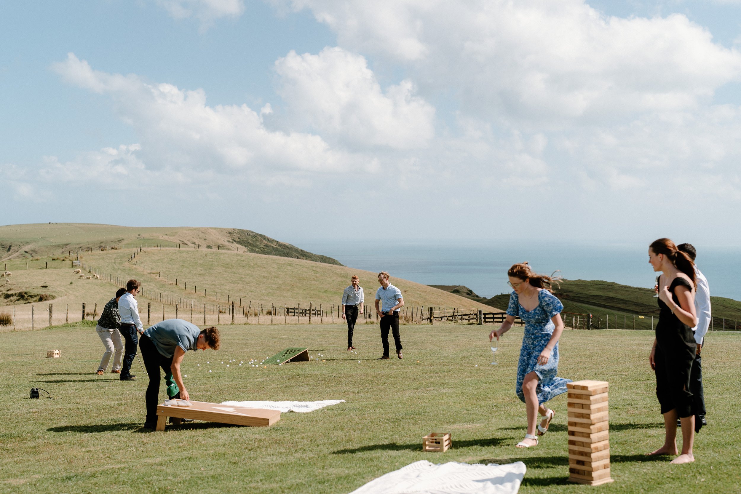 Group of people playing outdoor lawn games on a coastal hillside overlooking the ocean