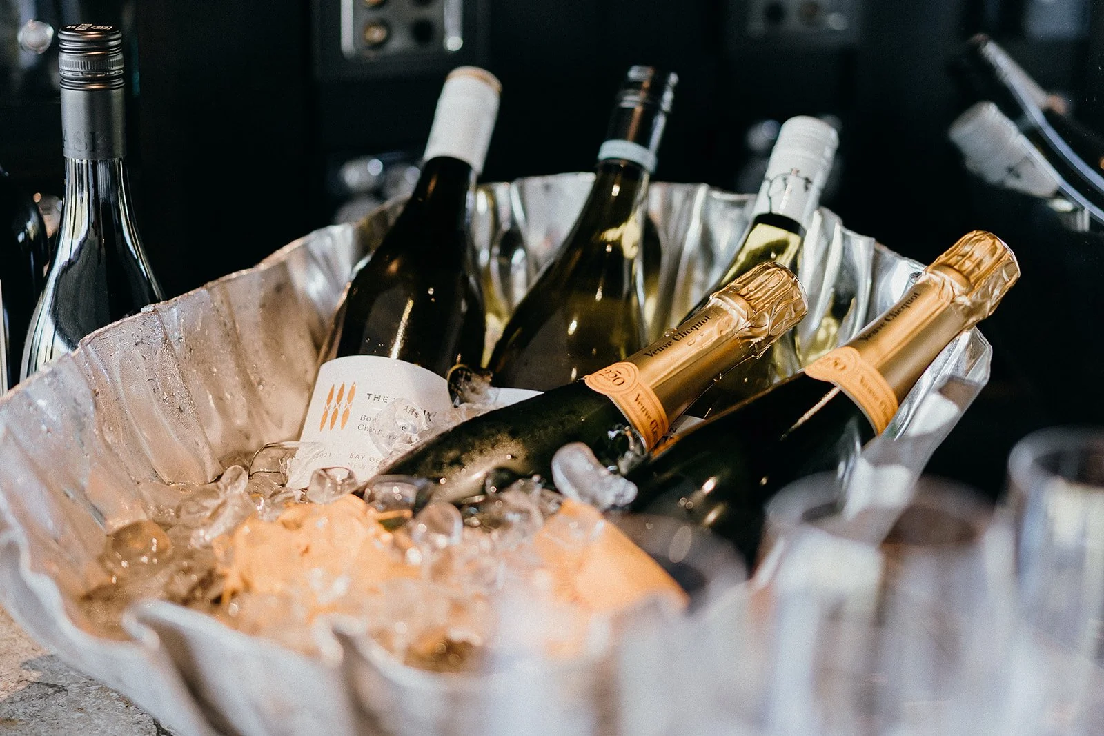 Assorted champagne and wine bottles chilling in an ice-filled metal bucket