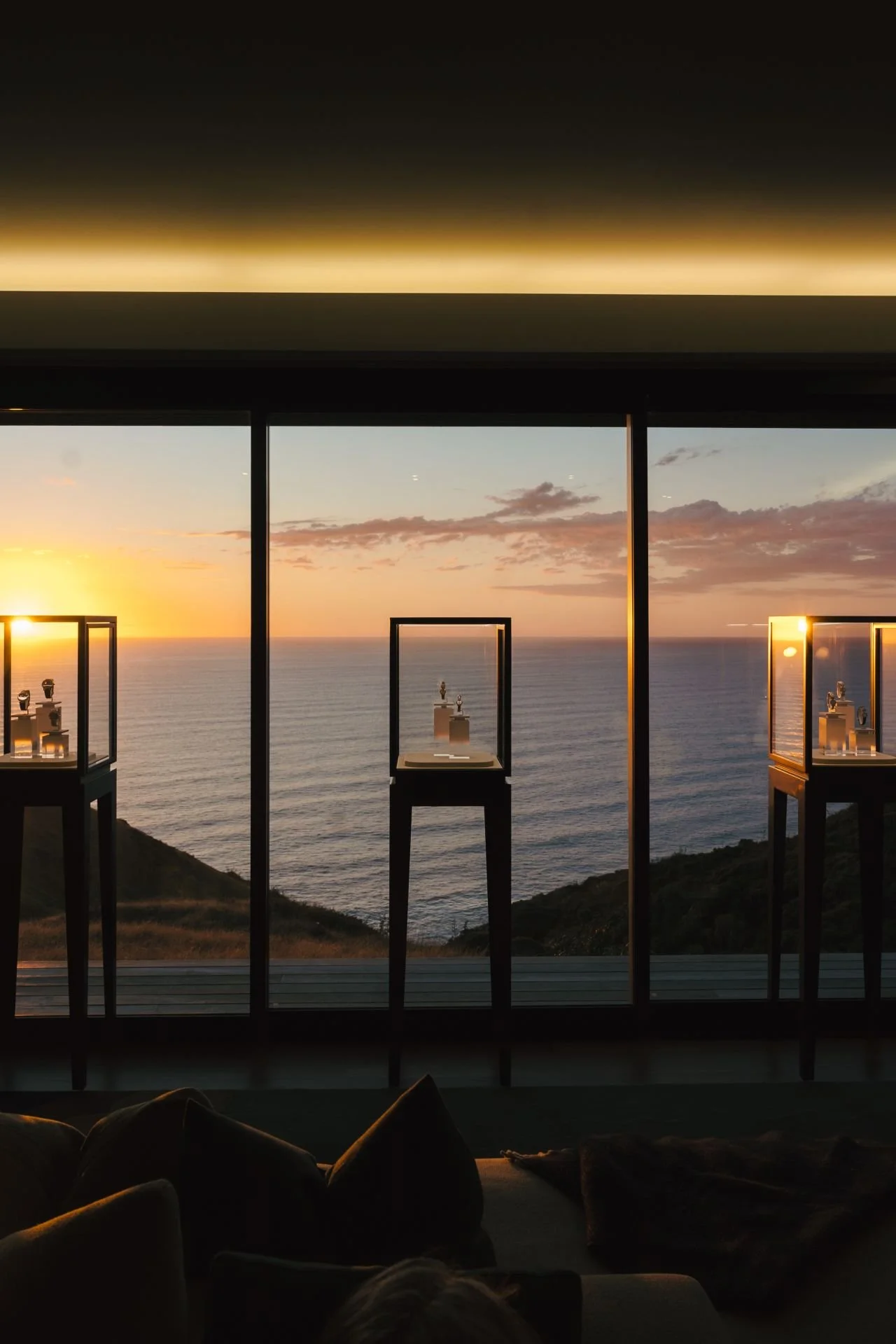 Glass display cases with Cartier watches overlooking the ocean at sunset