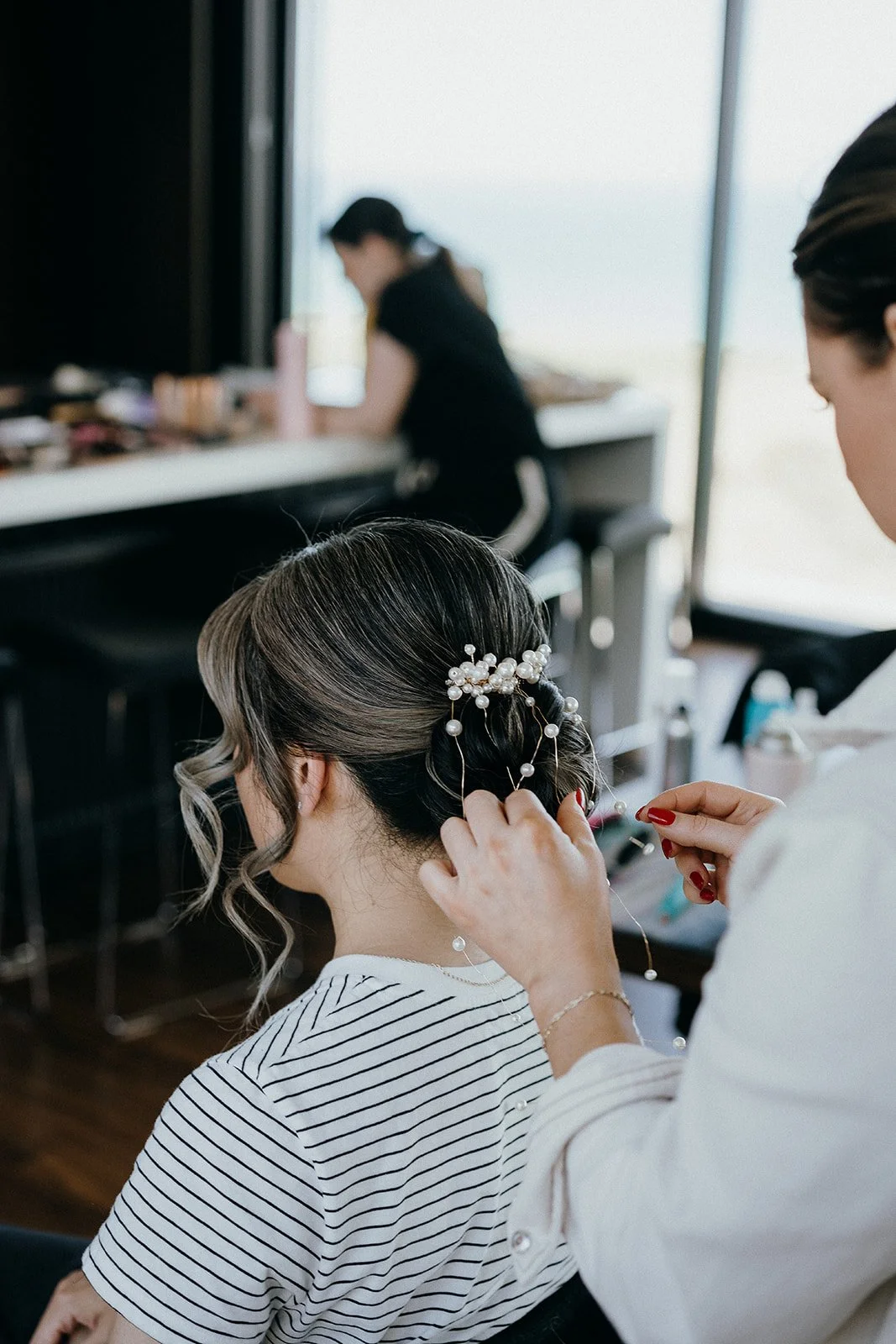 Stylist securing a pearl hair accessory into a woman's elegant updo