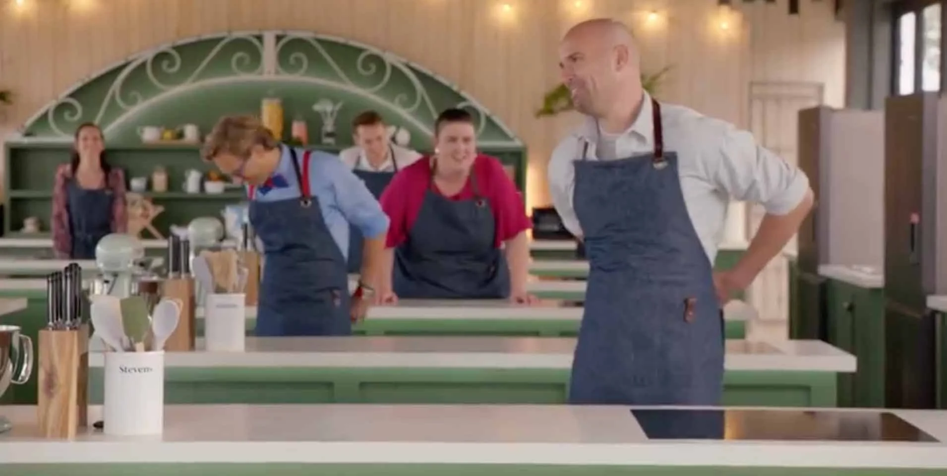 Group of chefs wearing aprons in a brightly lit kitchen studio