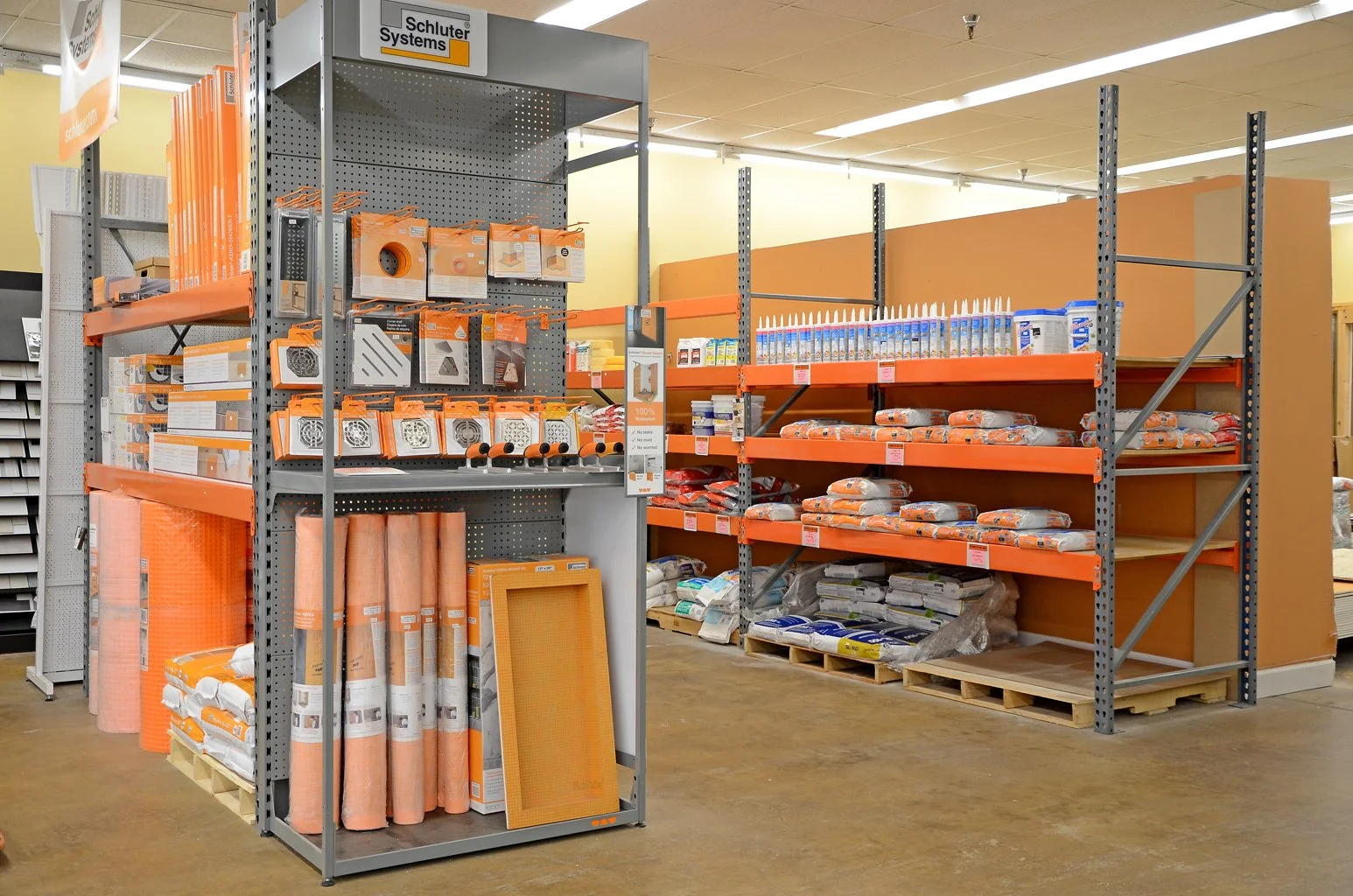 Home improvement store aisle with shelving units stocked with insulation, caulk, spray foam, and other construction materials.