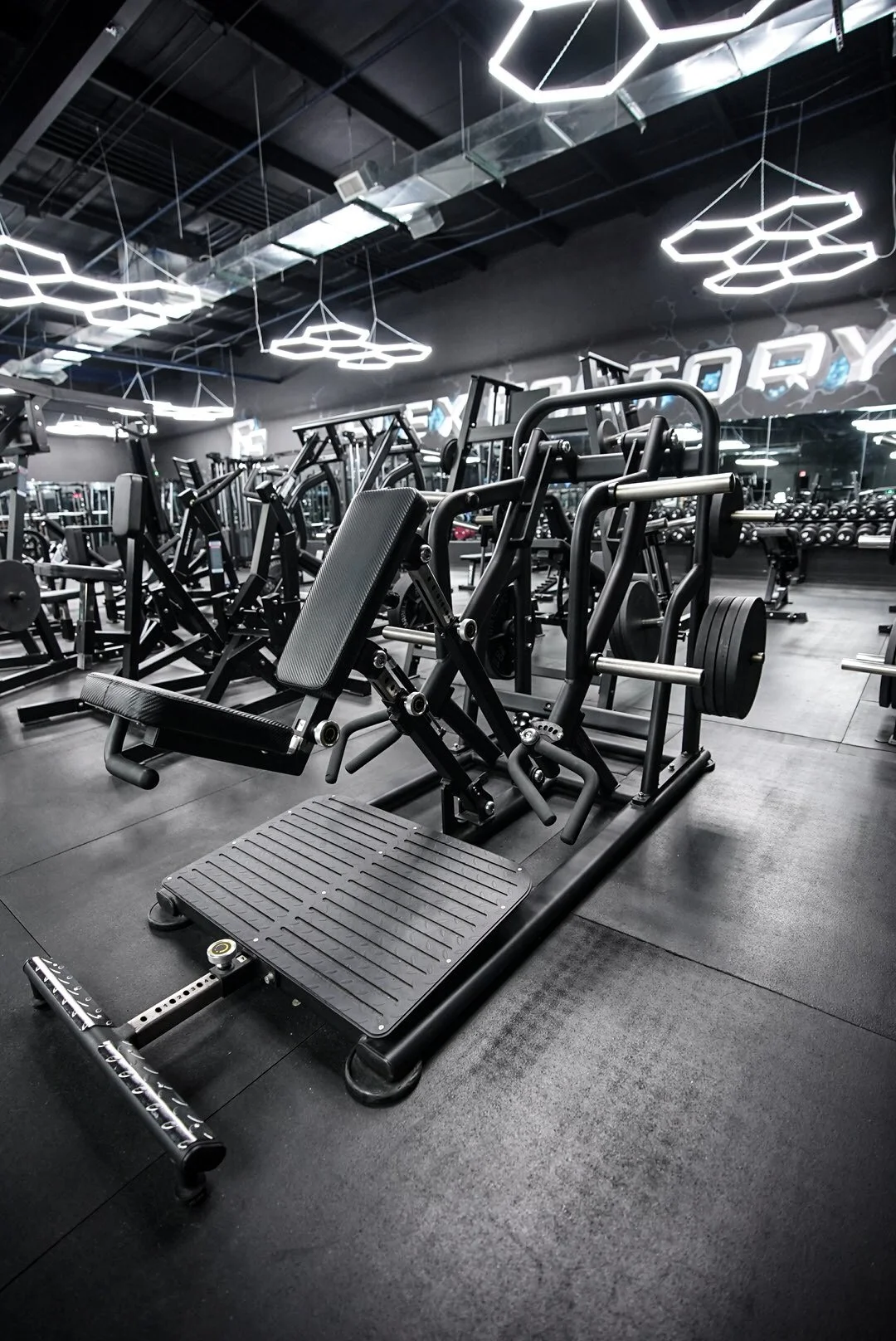 A modern gym with black equipment and hexagon-shaped ceiling lights