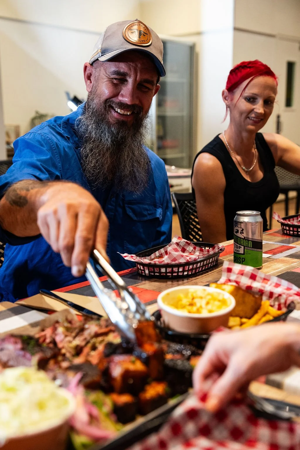People enjoying a meal at Smokey J's Texas BBQ in Coolalinga with food, drinks, and utensils, smiling and socializing.