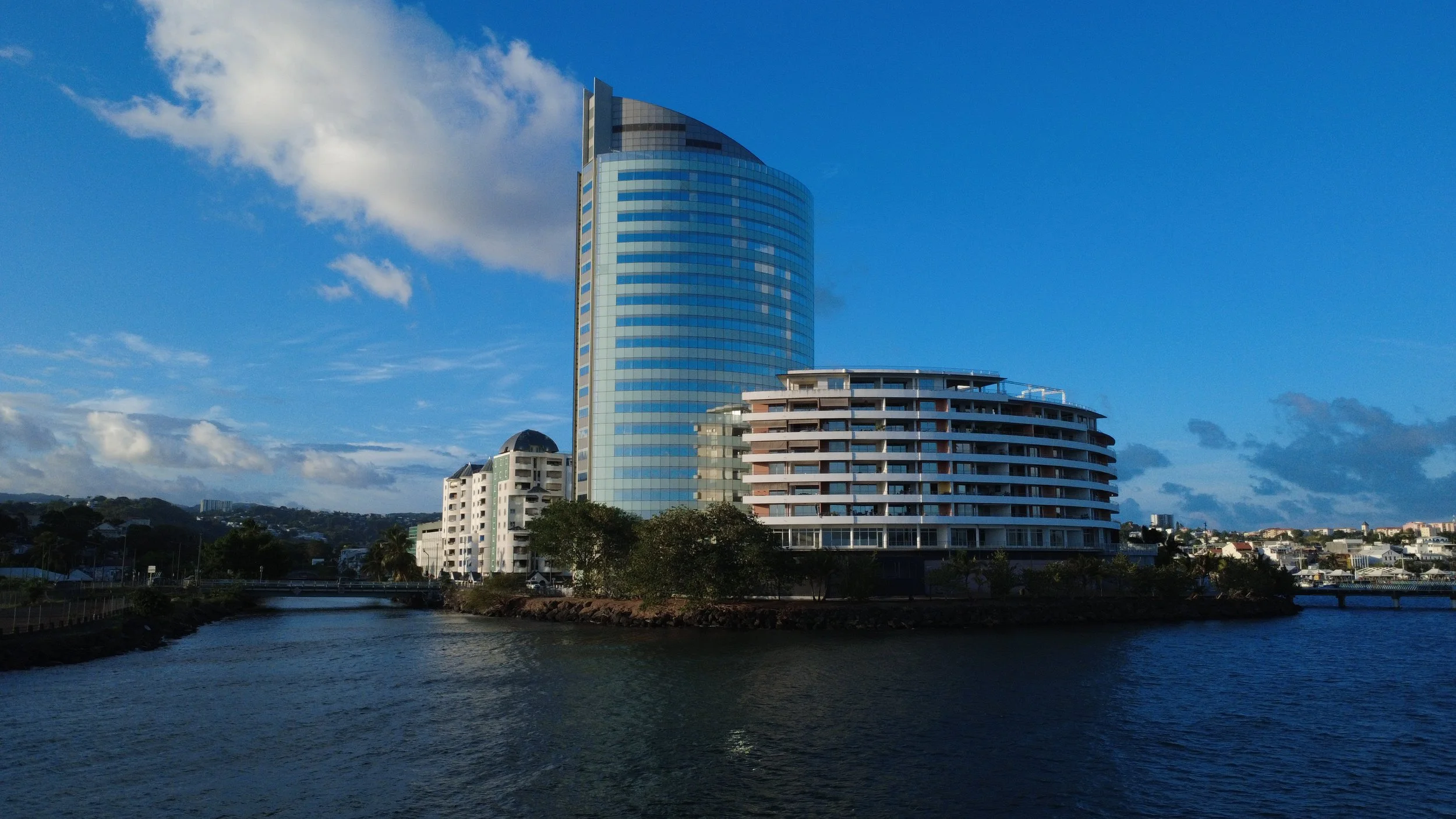Vue d'une ville avec un bâtiment moderne en verre et une rivière en premier plan.