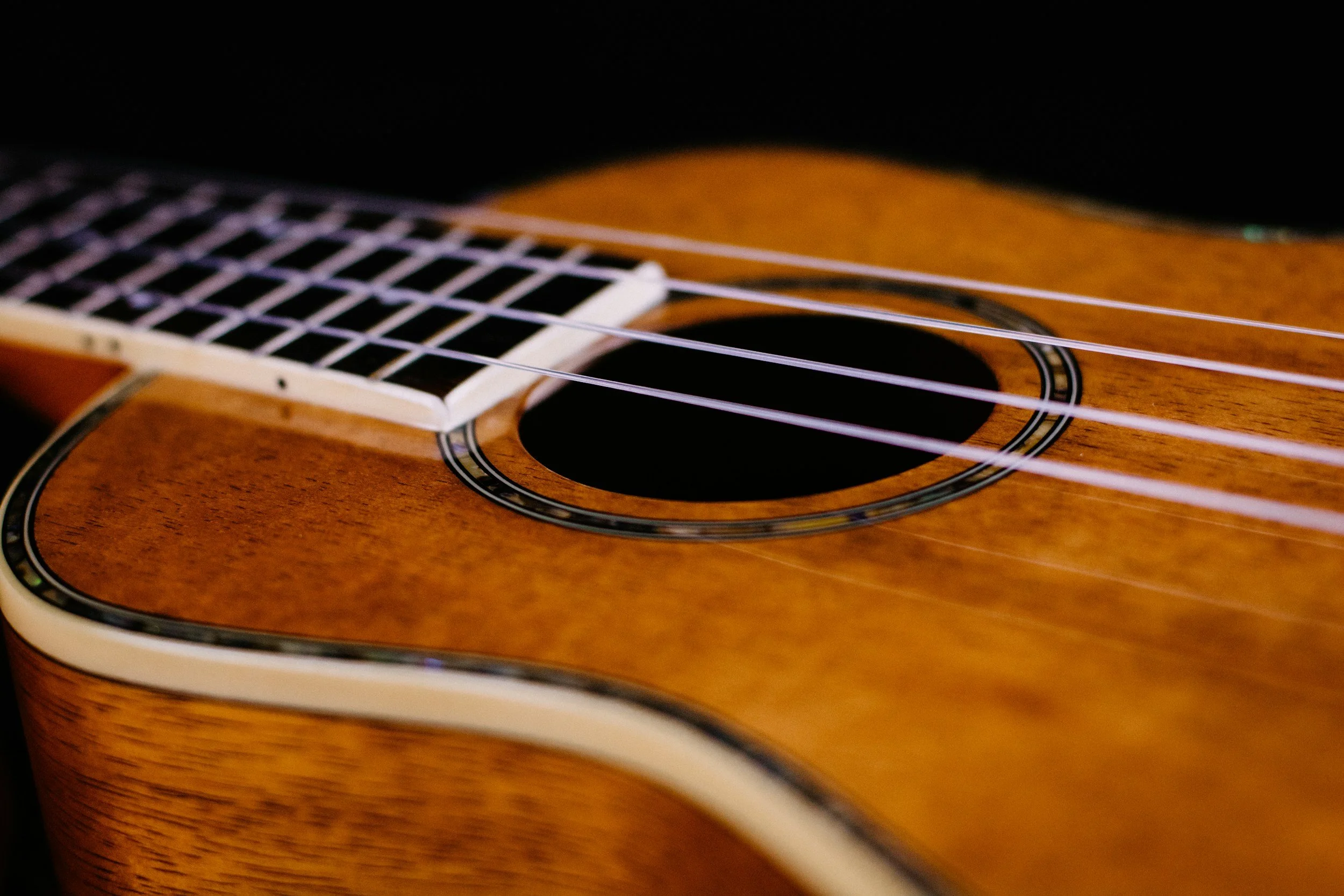 Close-up of a wooden acoustic guitar focusing on the sound hole and strings.