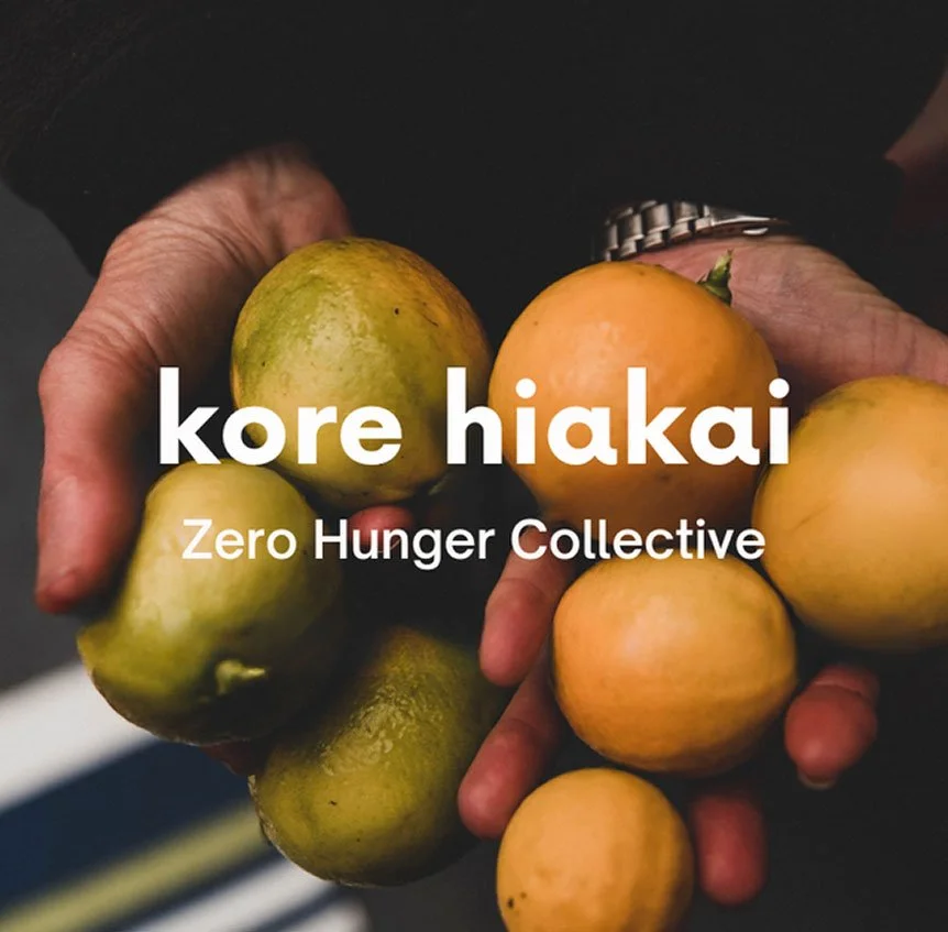 Person holding fresh, unripe green and yellow tomatoes with text overlay that reads 'kore hiakai Zero Hunger Collective'