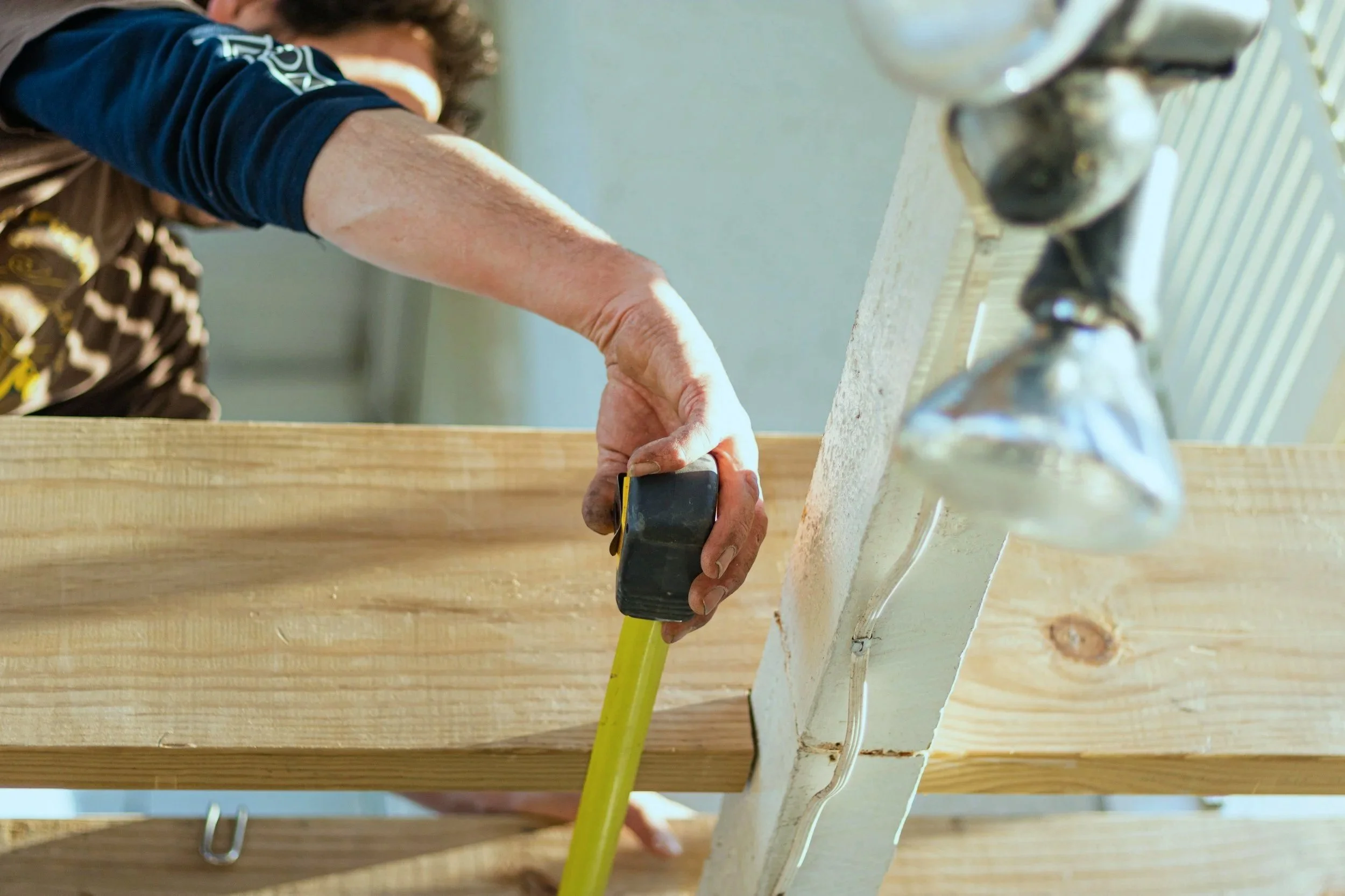 Tradie measuring timber on a New Zealand building project for accurate construction quantities and planning.