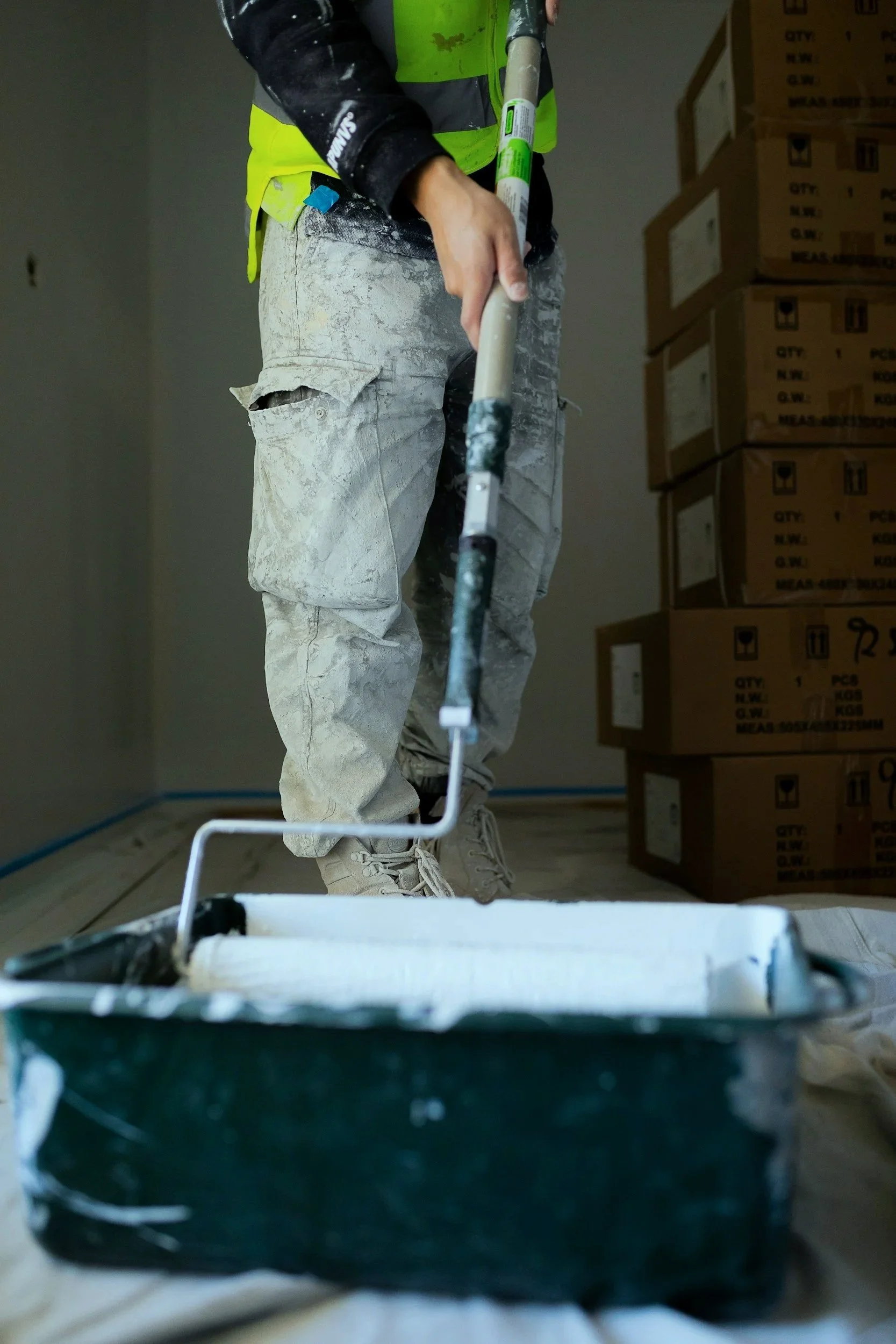 Tradie painting an interior wall on a New Zealand construction project using a paint roller.