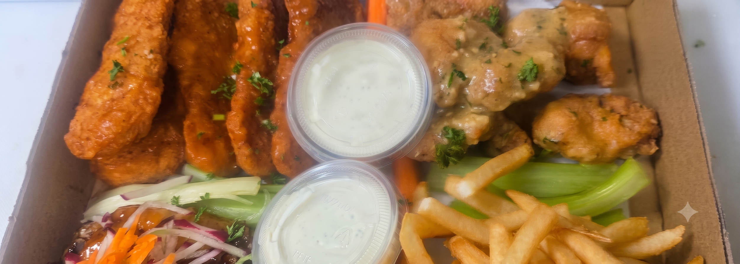 Fried chicken wings with sauce, fried chicken bites, celery, and carrot sticks, served with French fries and two small containers of dipping sauce