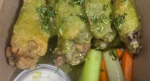 Spring rolls garnished with chopped herbs, served with carrots, celery, and a dipping sauce.
