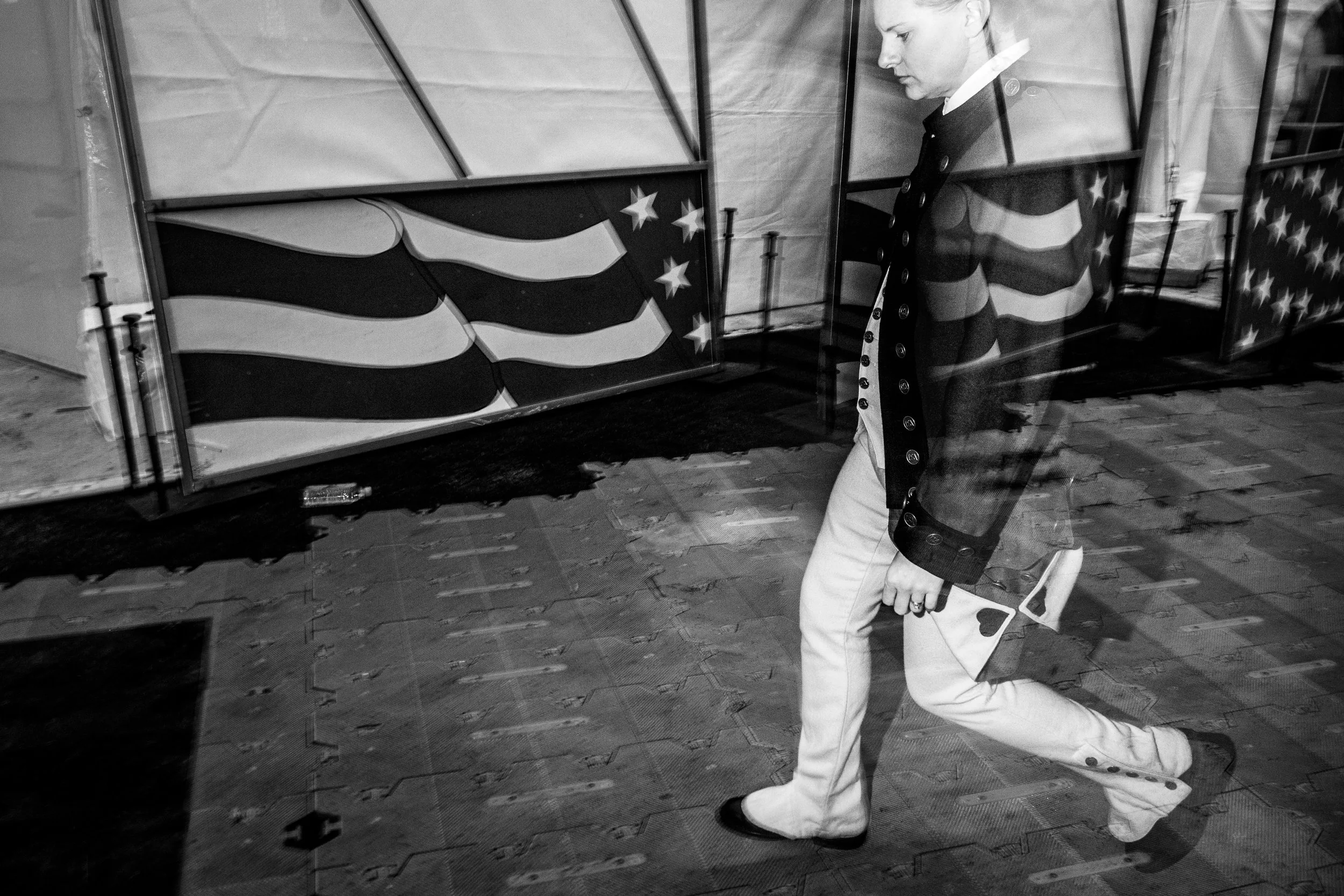 A person dressed in striped clothing and white pants is walking past a display case decorated with stars and stripes, resembling the American flag.