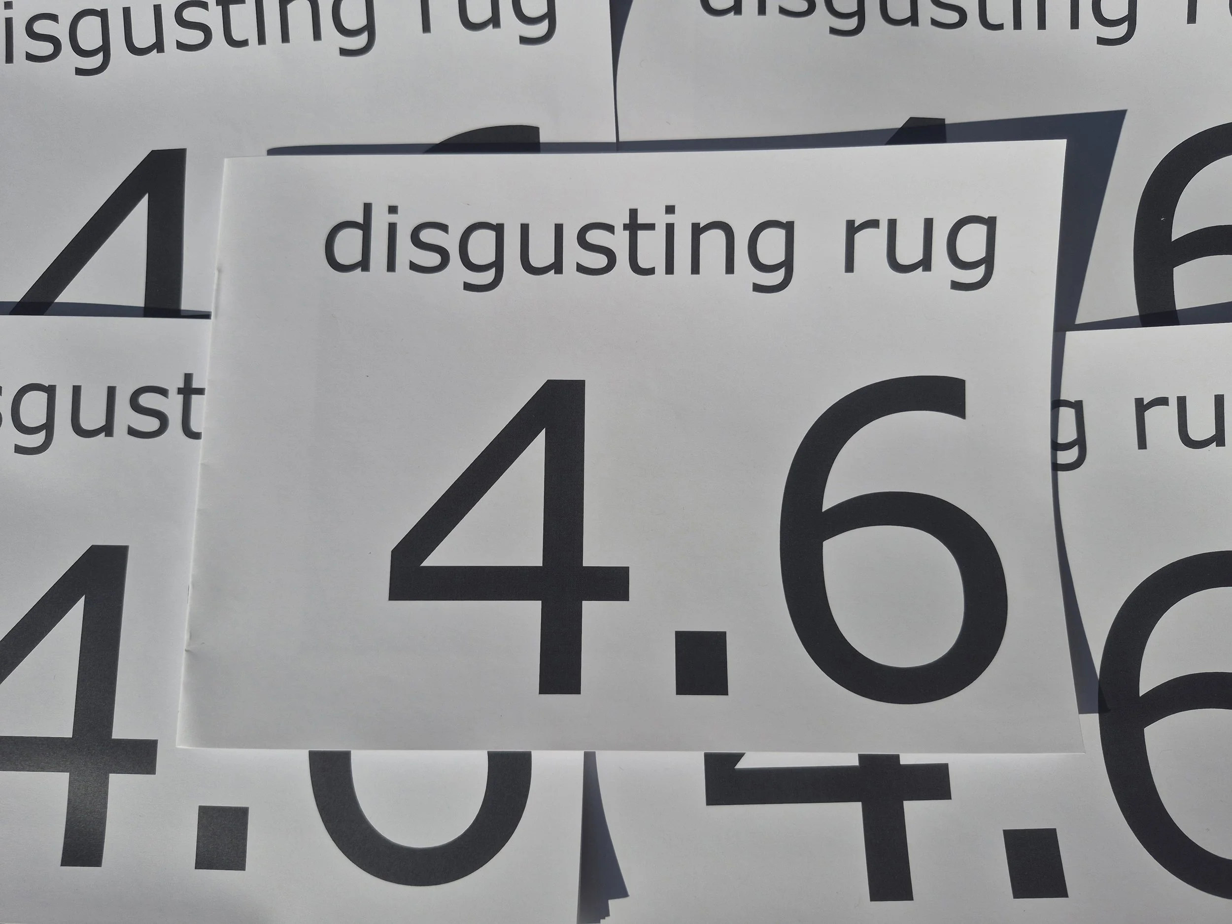 Close-up of multiple overlapping signs with large black numbers and words like 'disgusting rug' on white backgrounds.