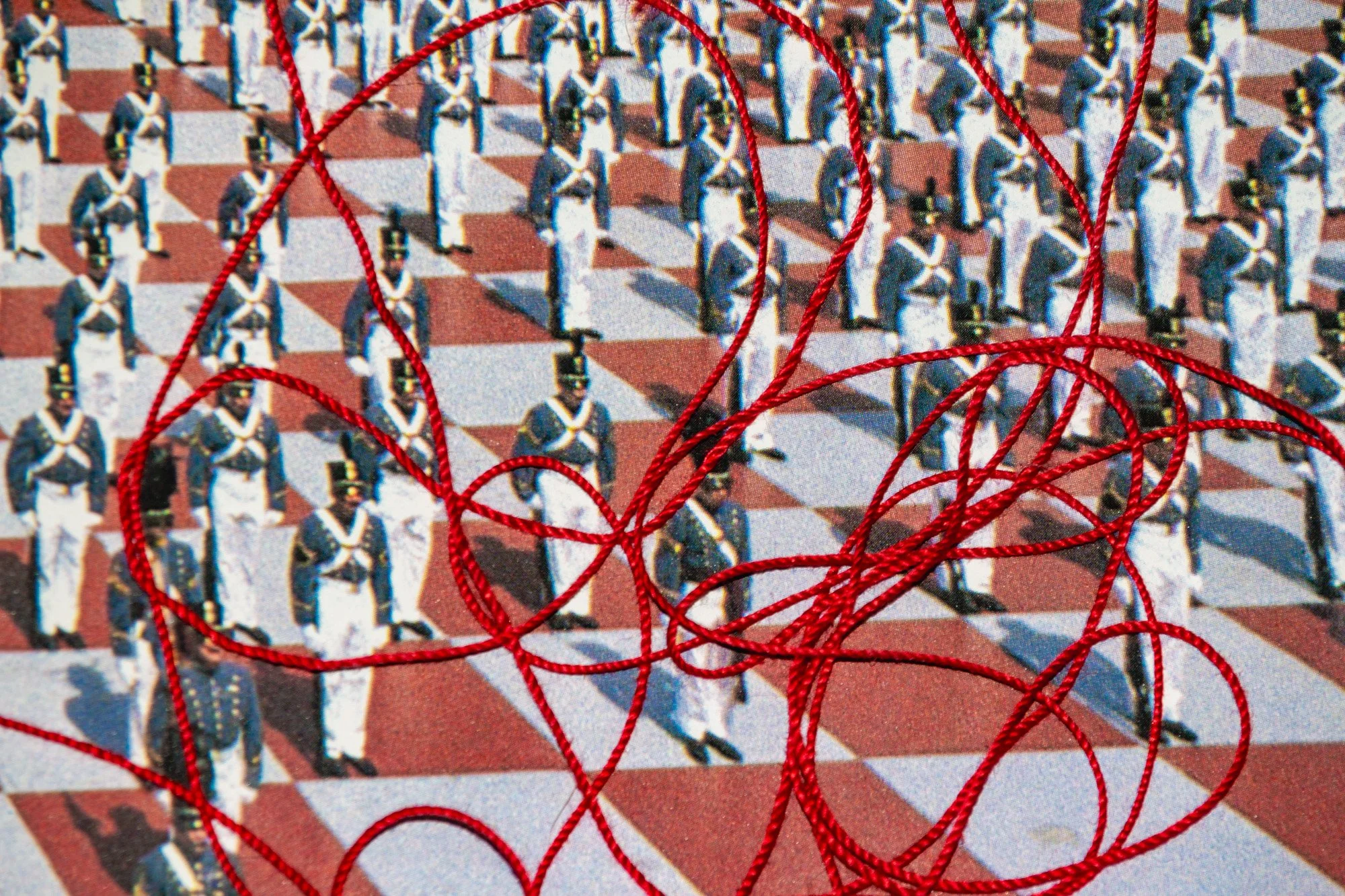 Image of soldiers in uniform standing in formation on a checkered ground pattern, with red string tangled in the foreground.