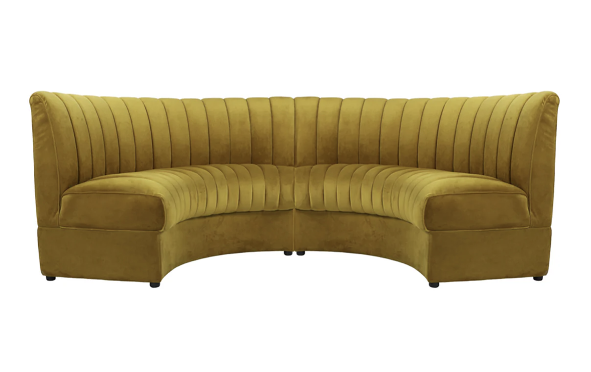 Yellow velvet curved sofa with vertical tufting.