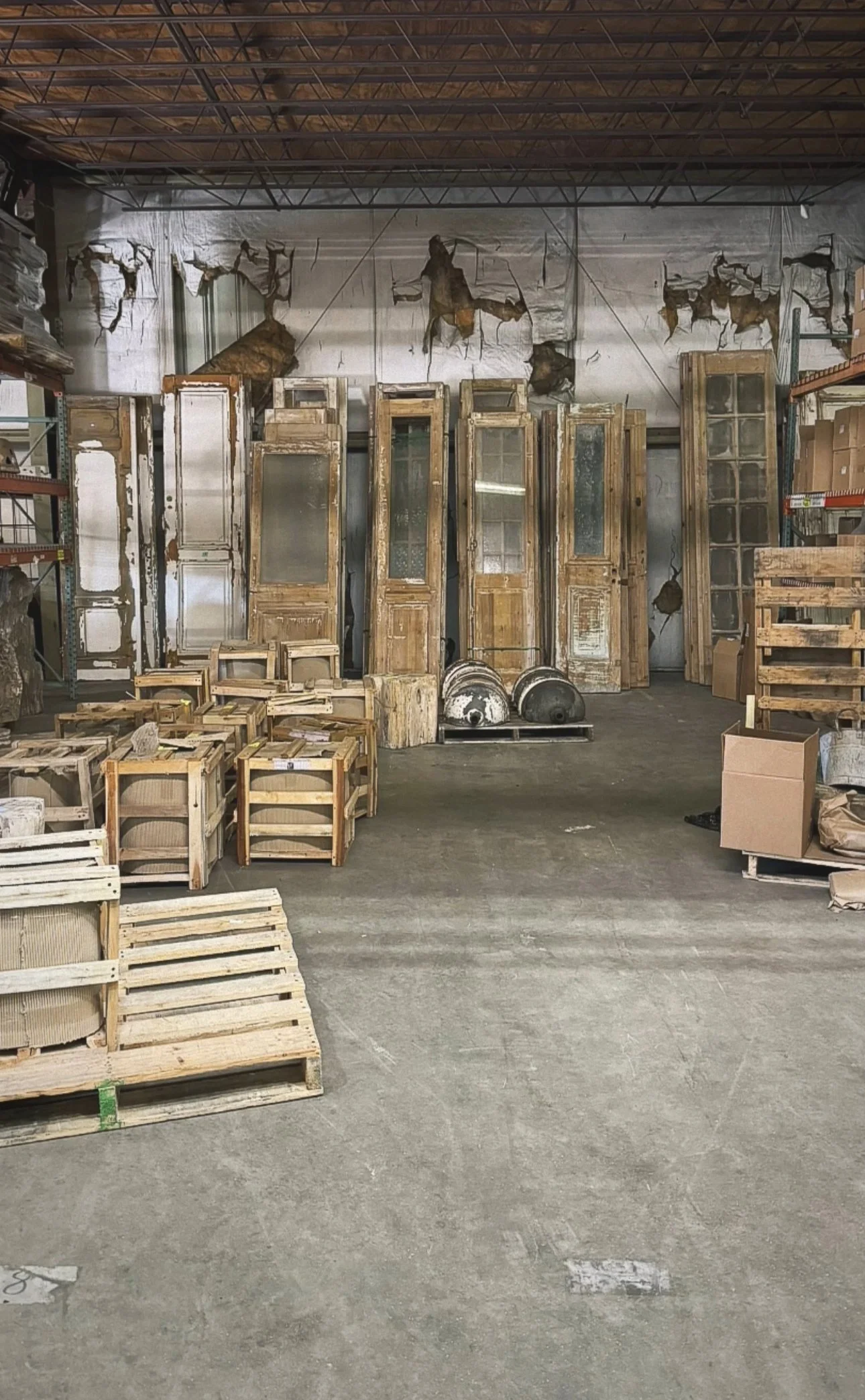 Warehouse with old wooden doors, wooden pallets, and miscellaneous materials.