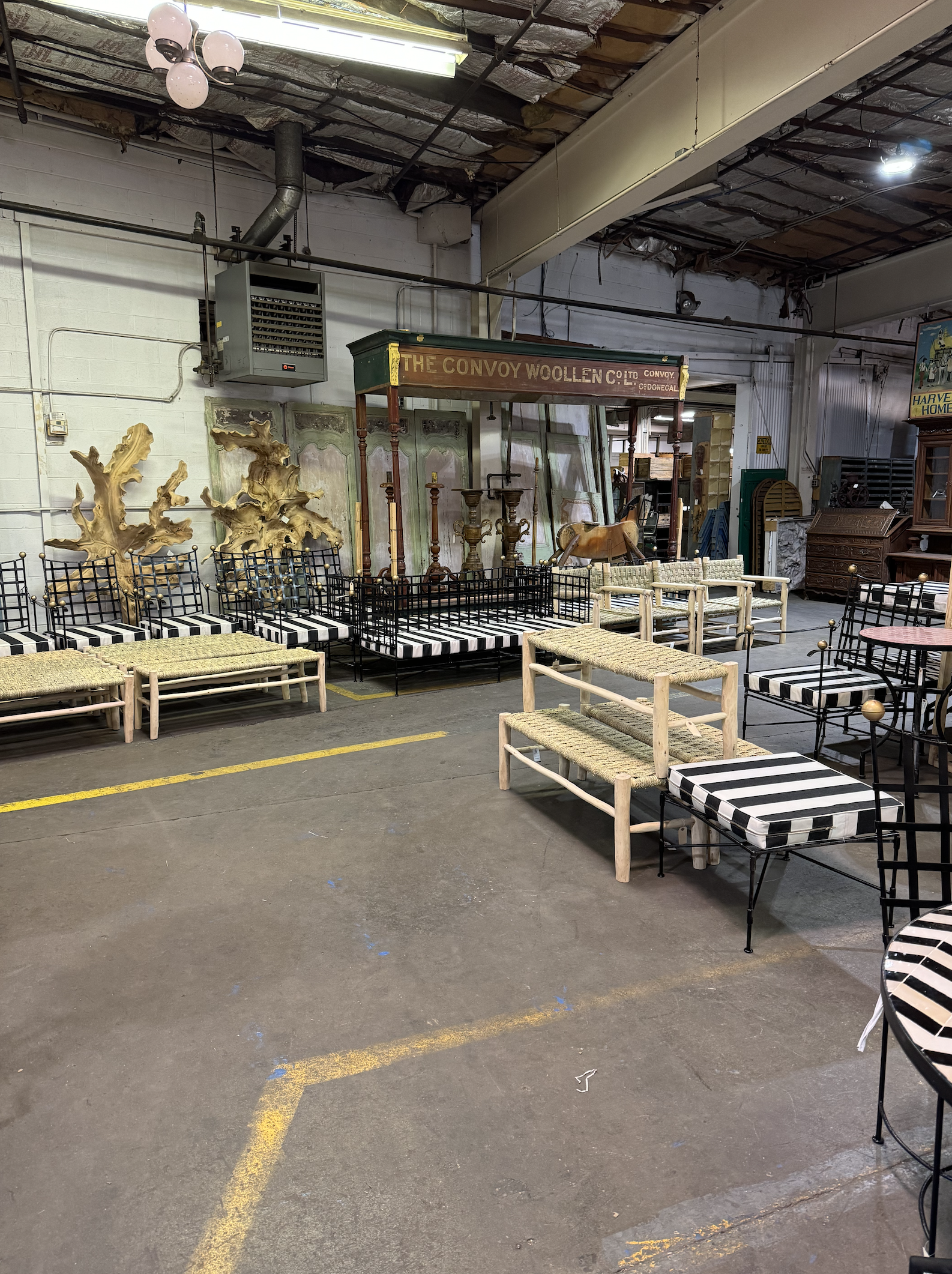 Interior of an antique store with assorted vintage furniture including chairs, benches, and wooden decorative items.