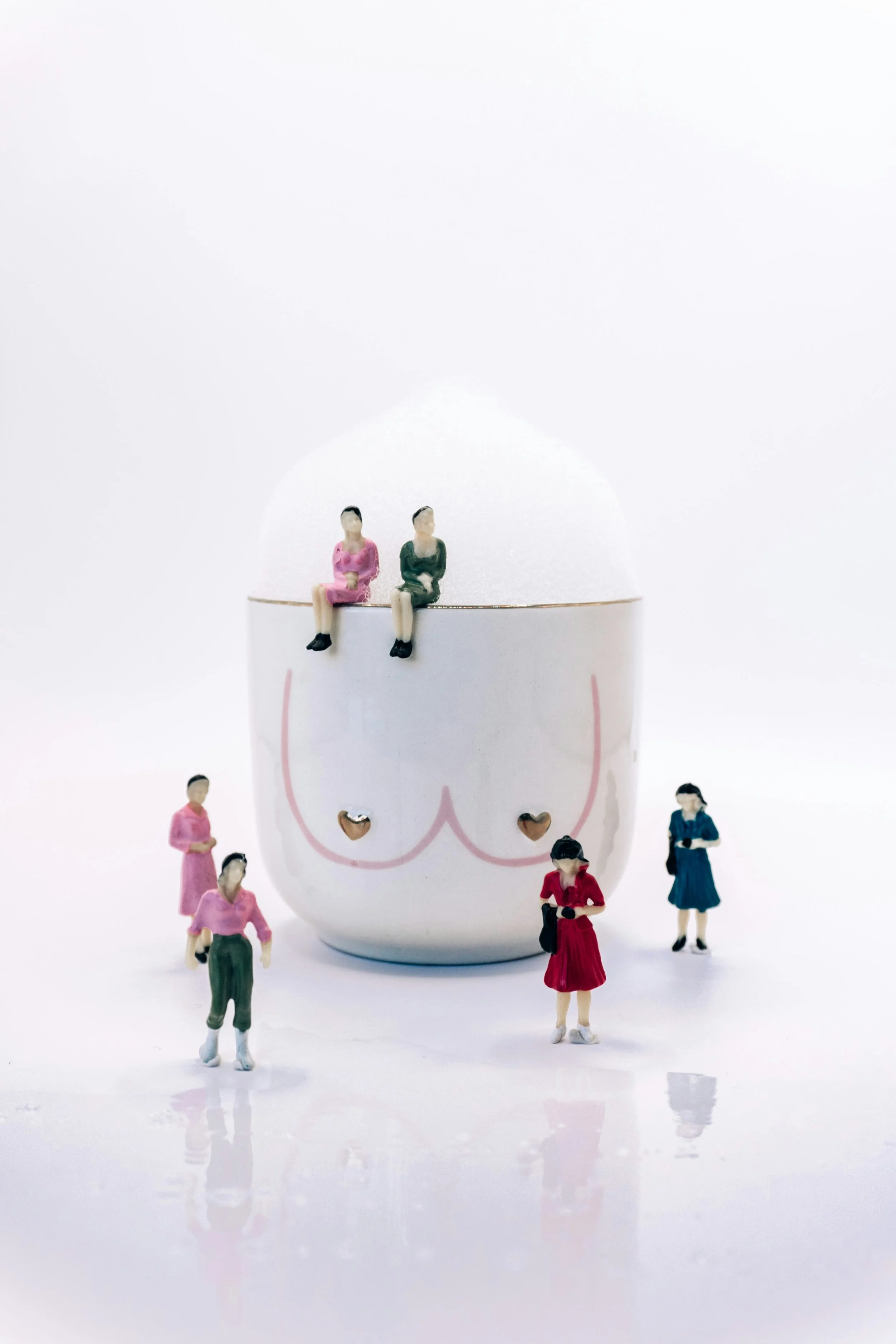 Tasse mit Brustillustration, darauf und daneben Miniaturfiguren