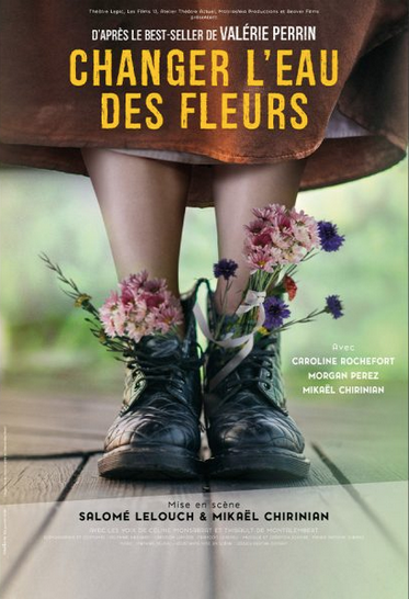 Une personne portant des bottes en cuir, avec des fleurs roses et violettes sortant de ses chaussures, debout sur un plancher en bois.