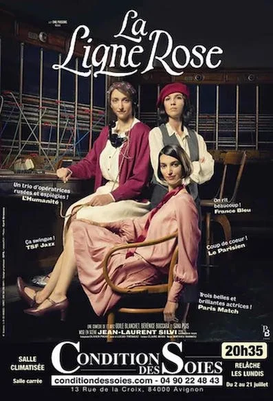 Trois femmes sur une affiche de spectacle intitulée "La Ligne Rose" dans un théâtre, avec des étagères de costumes en arrière-plan.