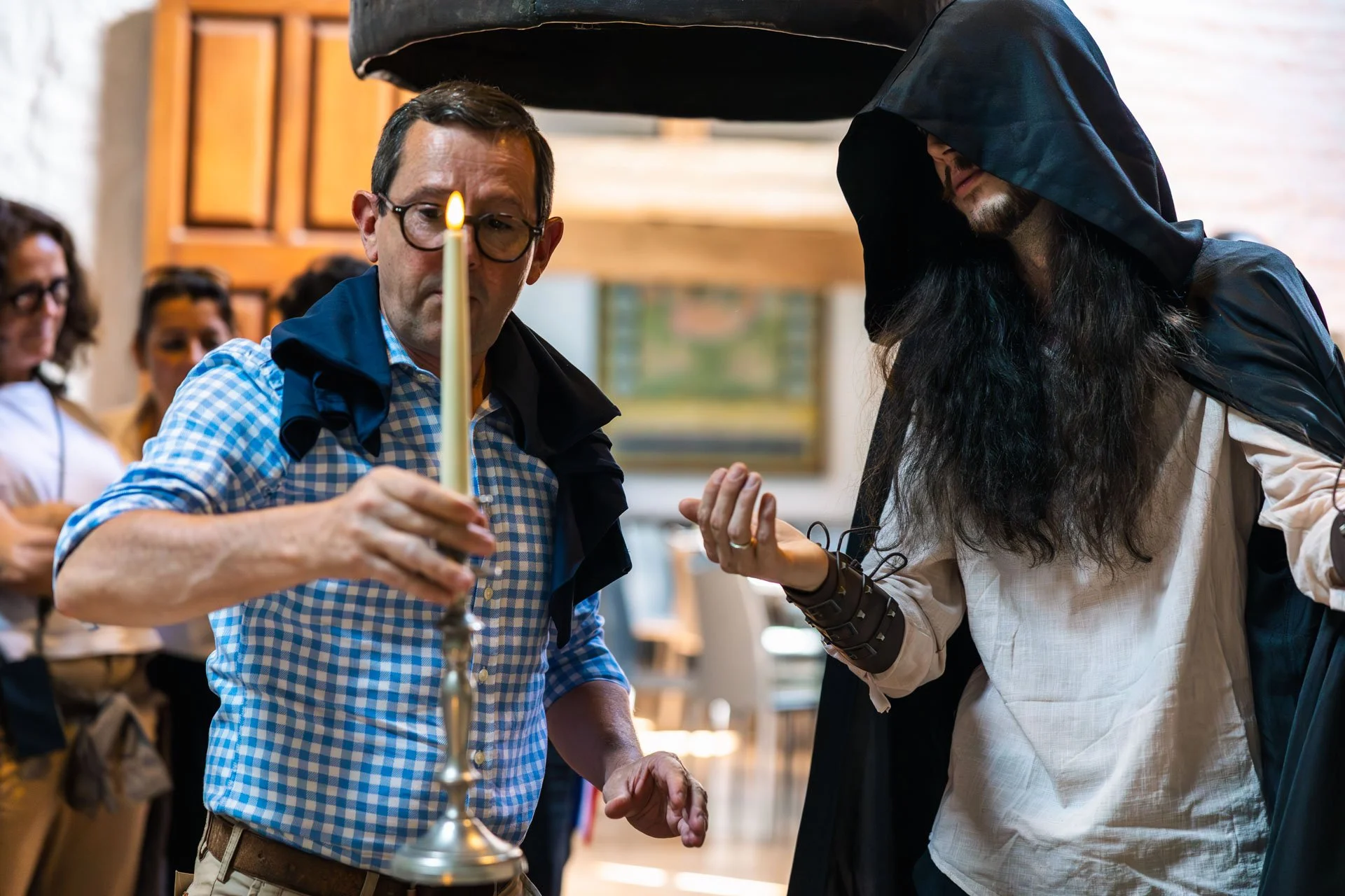 Deux hommes vêtus de robes et capes lors d'une cérémonie religieuse, l'un d'eux tient une bougie allumée.