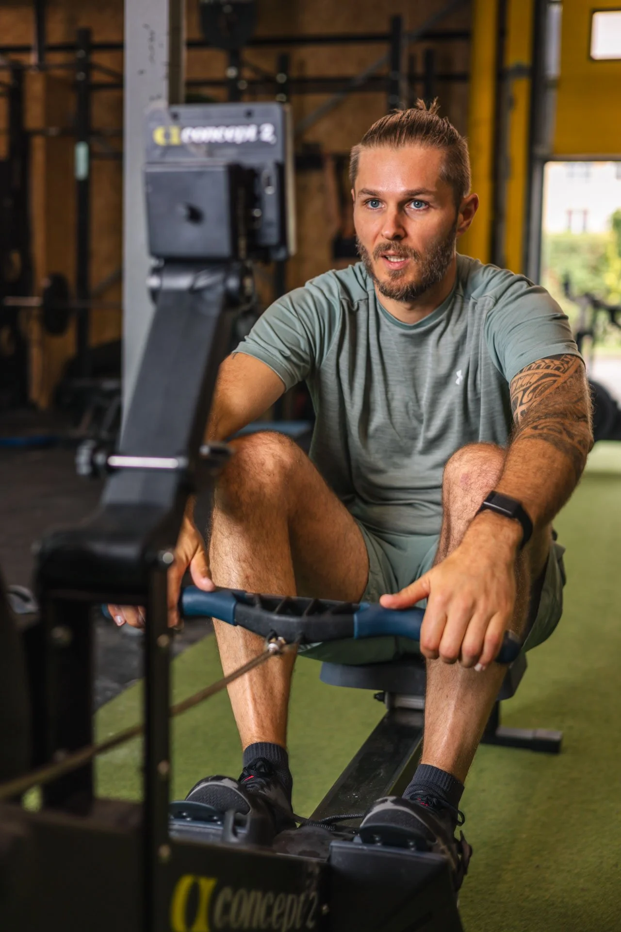 Un homme en tenue de sport utilise un rameur dans une salle de sport