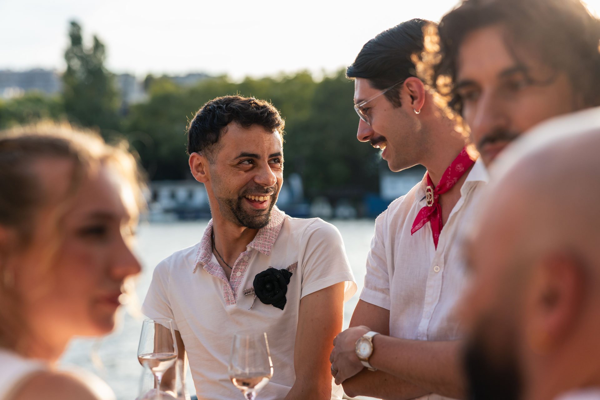 Groupe de personnes souriantes lors d'une rencontre en extérieur avec vue sur l'eau au coucher du soleil