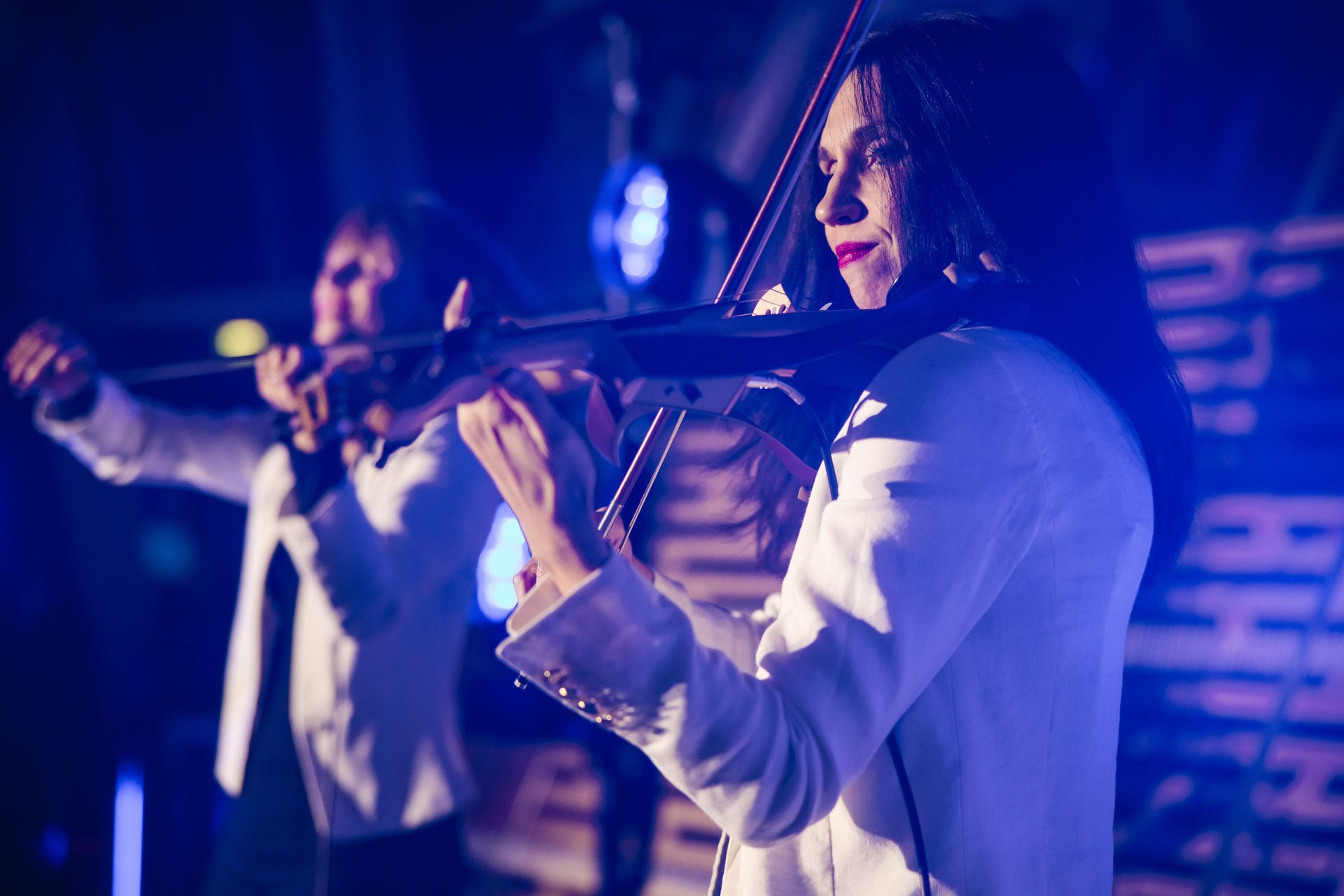 Femme jouant du violon dans un environnement sombre avec des lumières bleues.