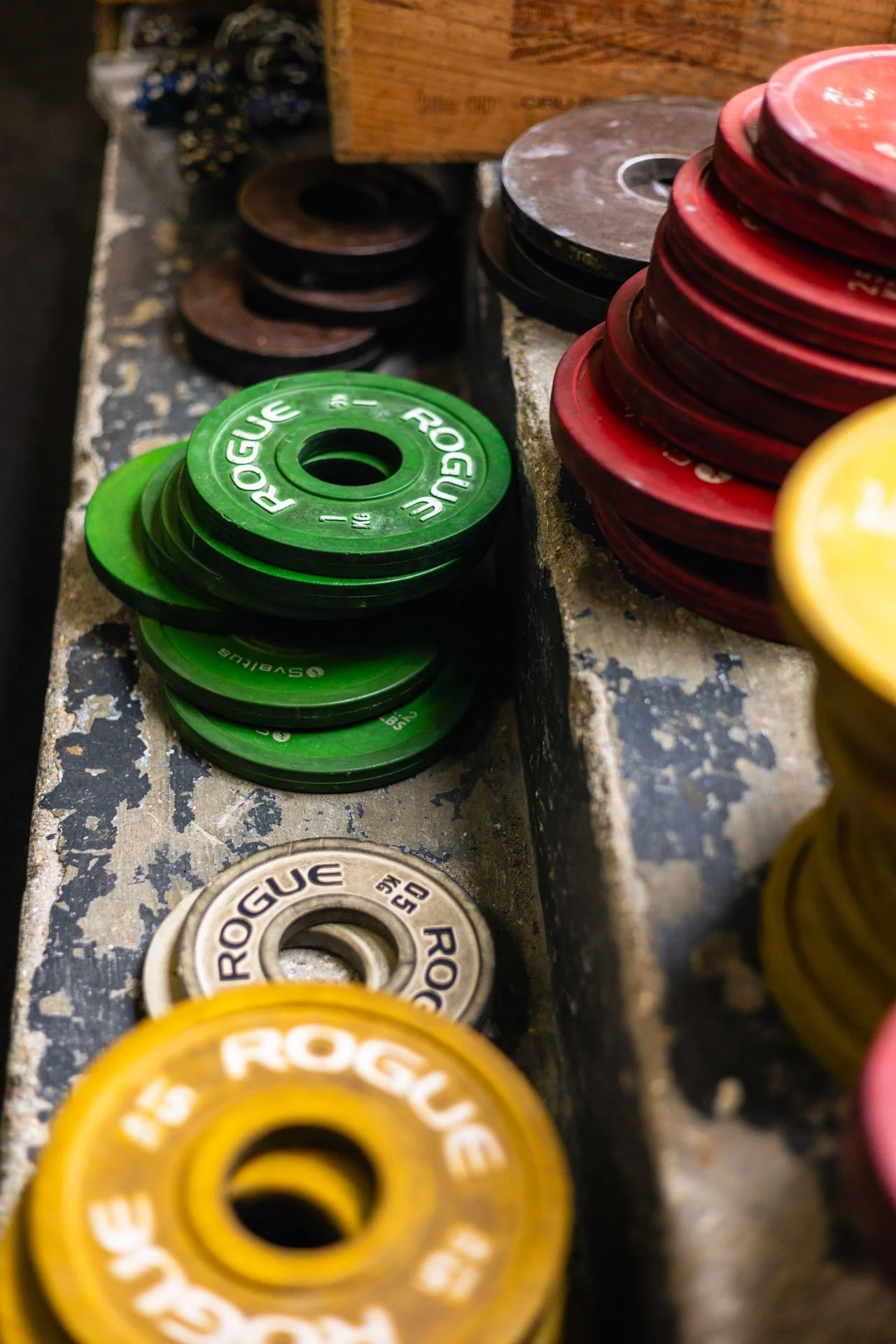 Des disques de poids de différentes couleurs empilés sur un banc de musculation. Vert, noir, rouge, jaune et argent, utilisés pour la musculation ou le weightlifting.