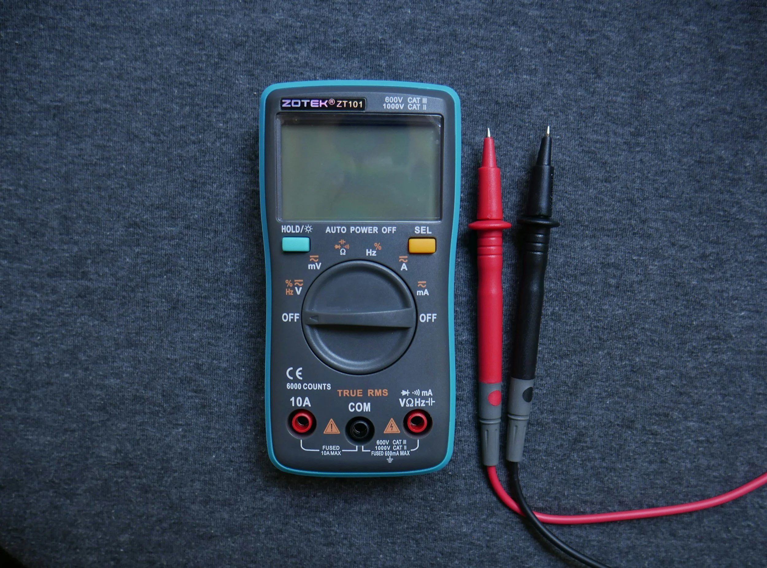 Ein Multimeter mit Verbindungskabeln auf einem schwarzen Stoffhintergrund.