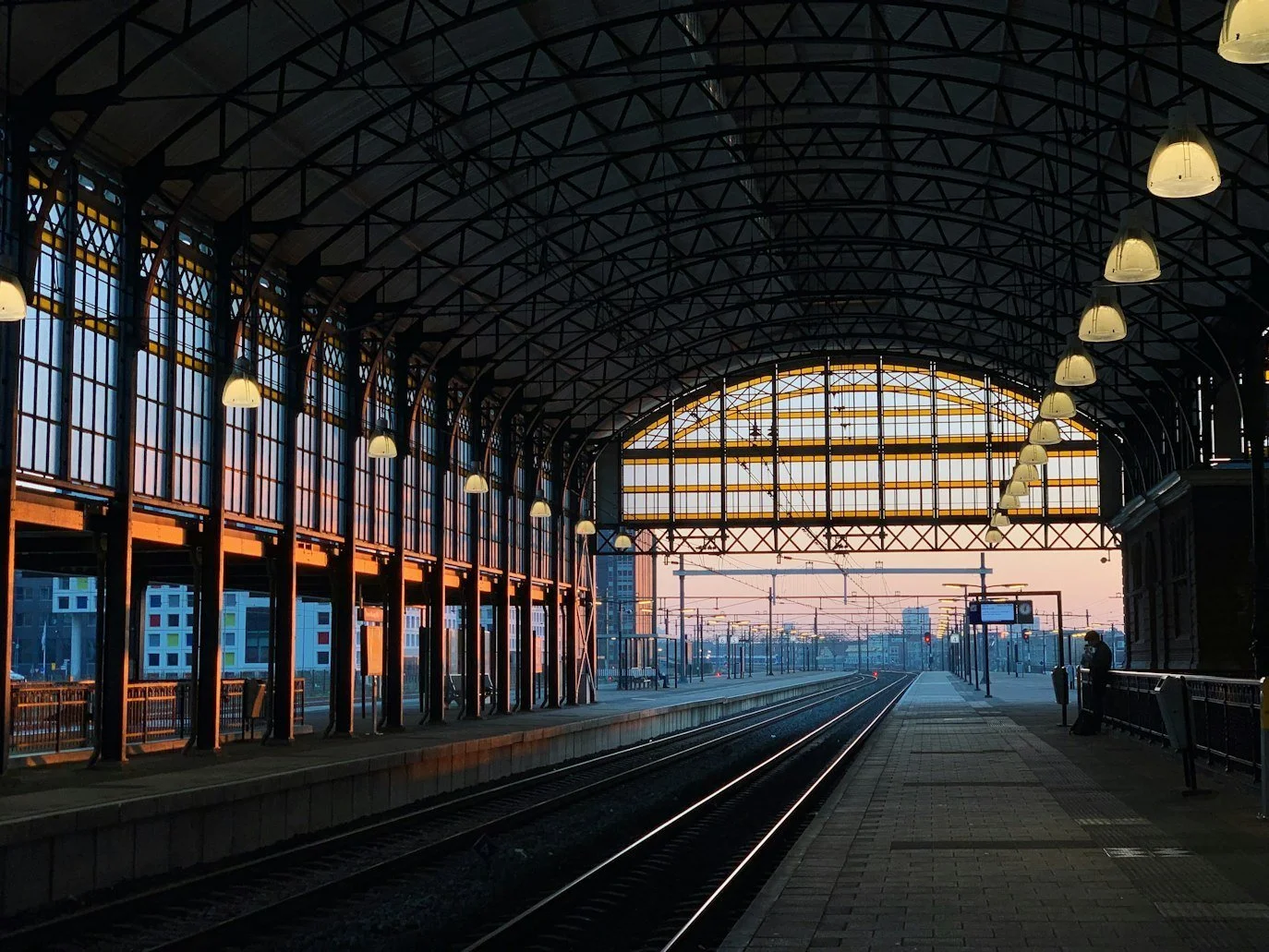 Rail platforms, passenger access and overhead lines beneath a station roof.