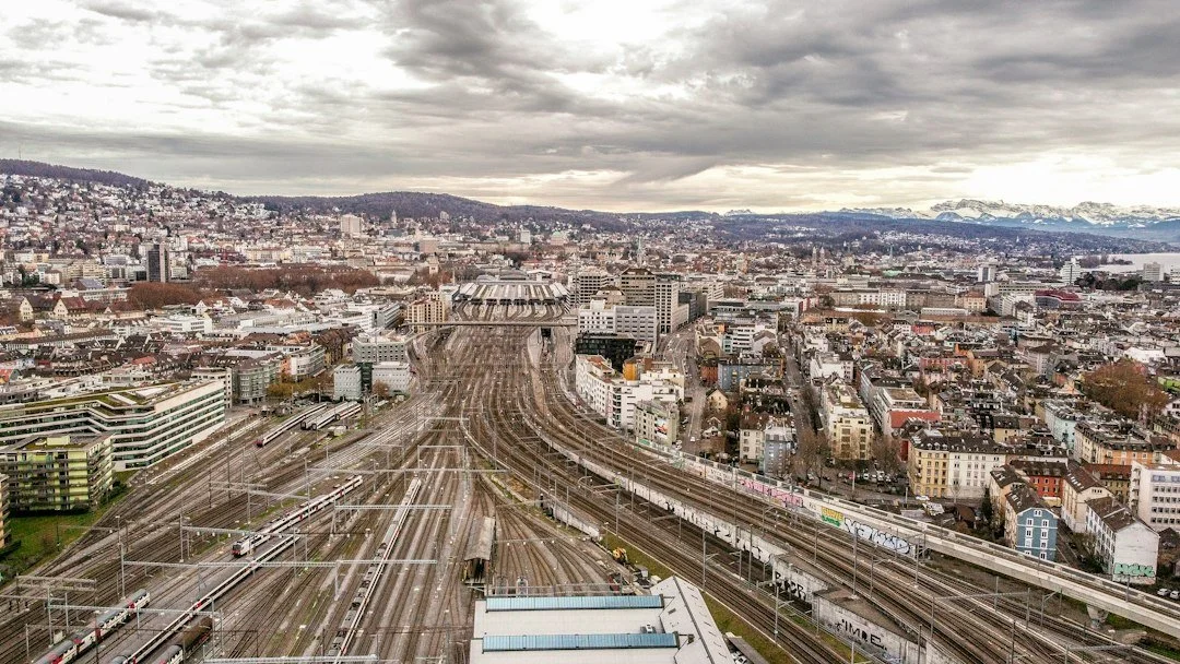Railway tracks and overhead lines converging beside an urban area.