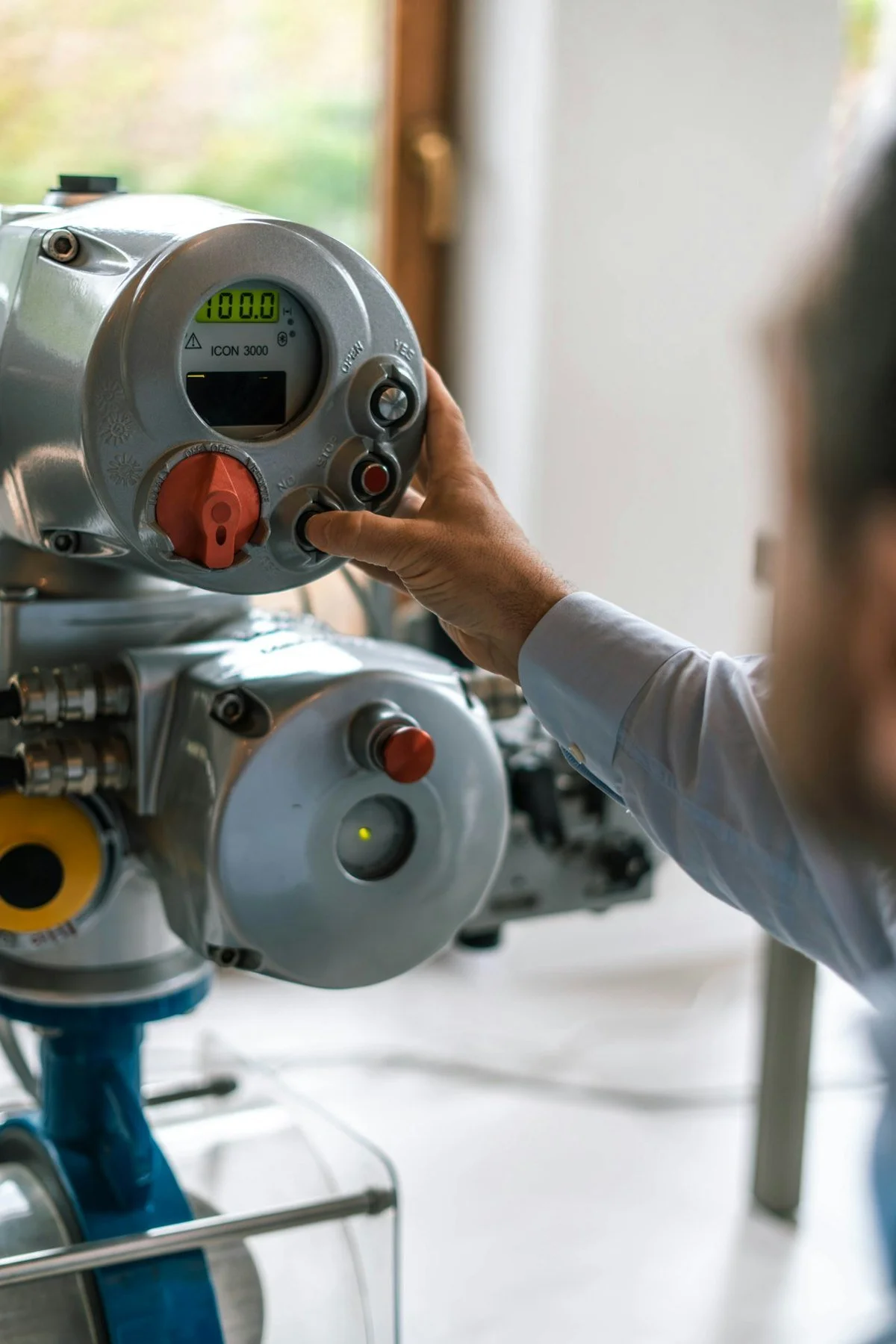 A person adjusting the local controls of an industrial valve actuator.