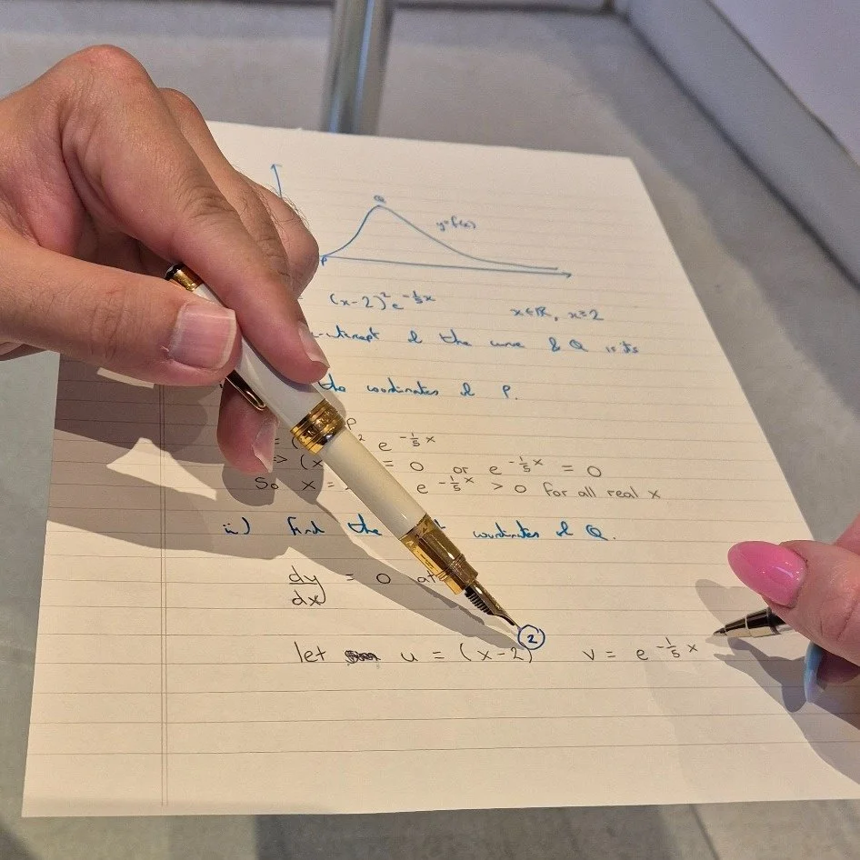 Two people working together on handwritten mathematics during a face-to-face tuition session.