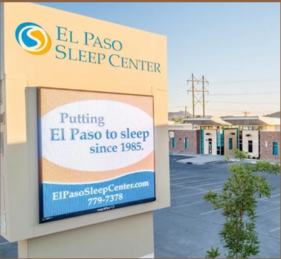 Sign for El Paso Sleep Center with slogan and contact information, located in a commercial area with neighboring buildings and power lines.
