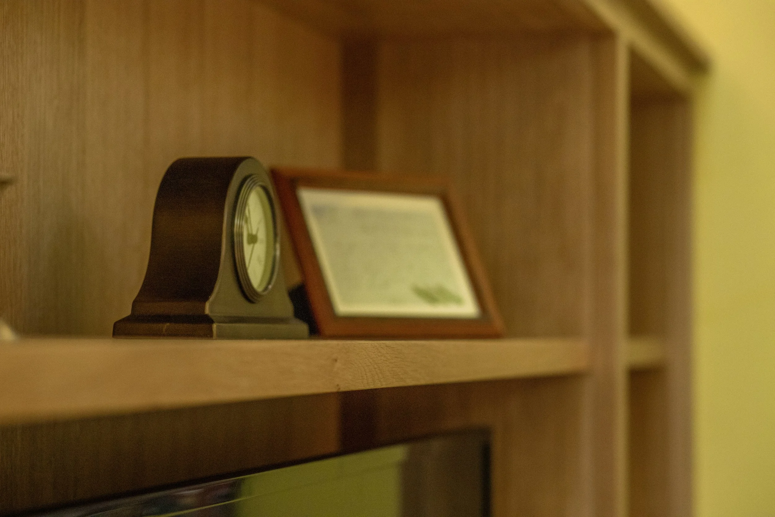 A wooden desk with a small clock and an picture frame.