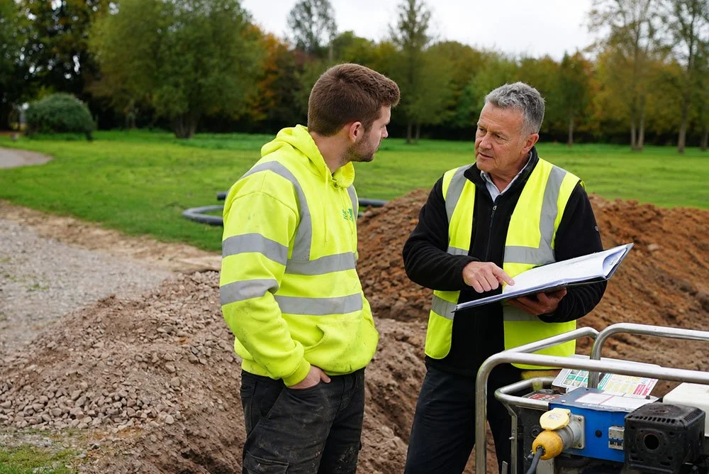 WES team reviewing site plans beside an excavation.